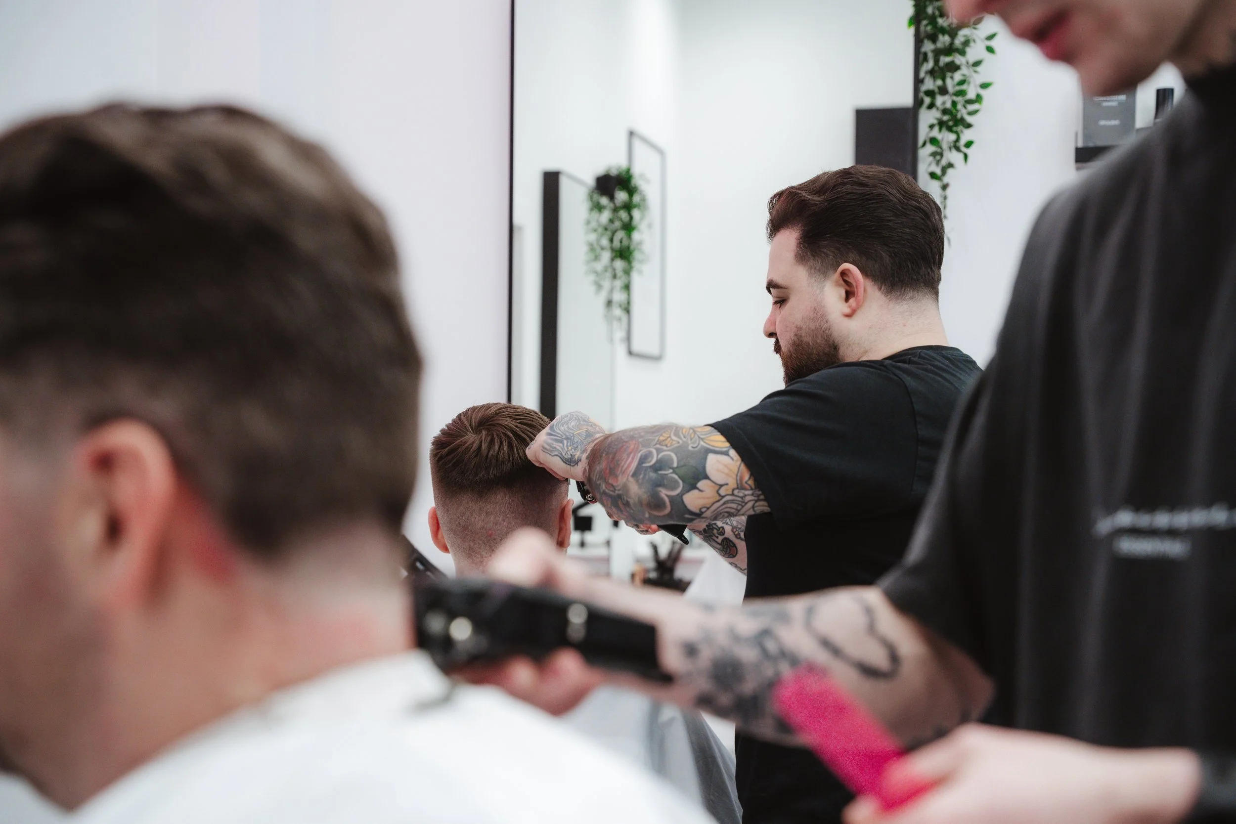 Barbers cutting clients' hair inside Connoisseurs Barbershop in Leith, Edinburgh