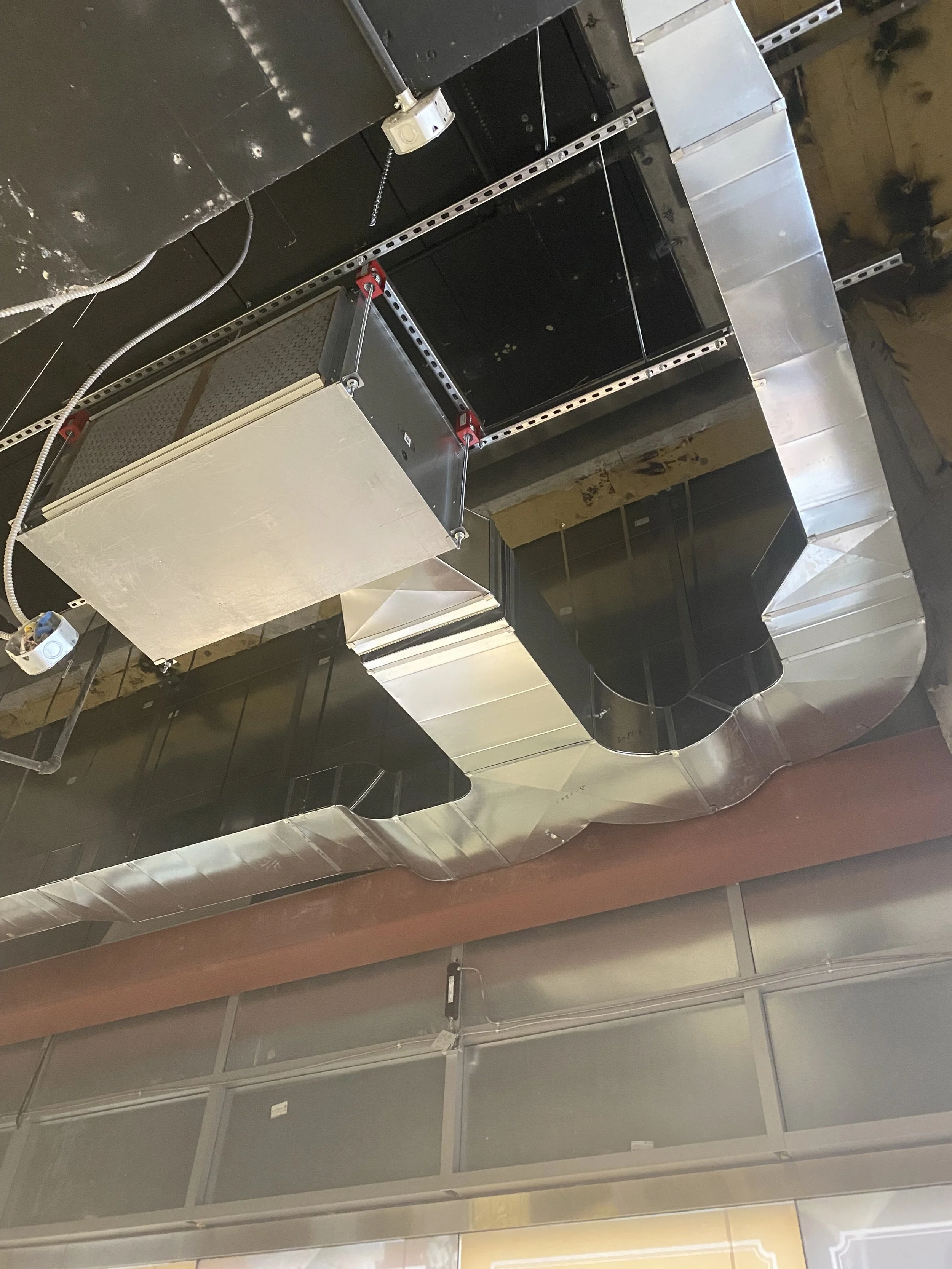 Ceiling with metal ductwork, black and silver air vents, and electrical wiring.