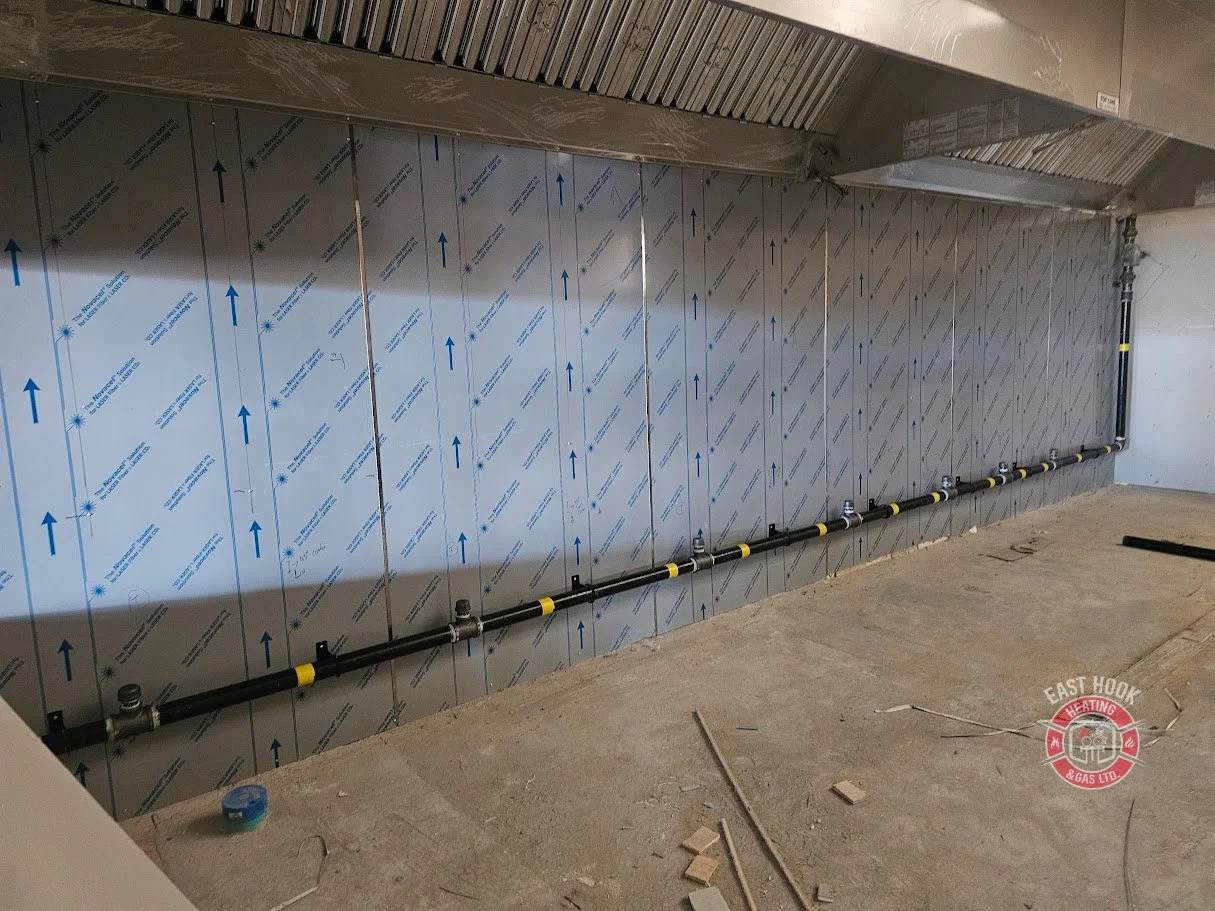 Construction site with insulated wall panels and plumbing pipes installed along the wall.