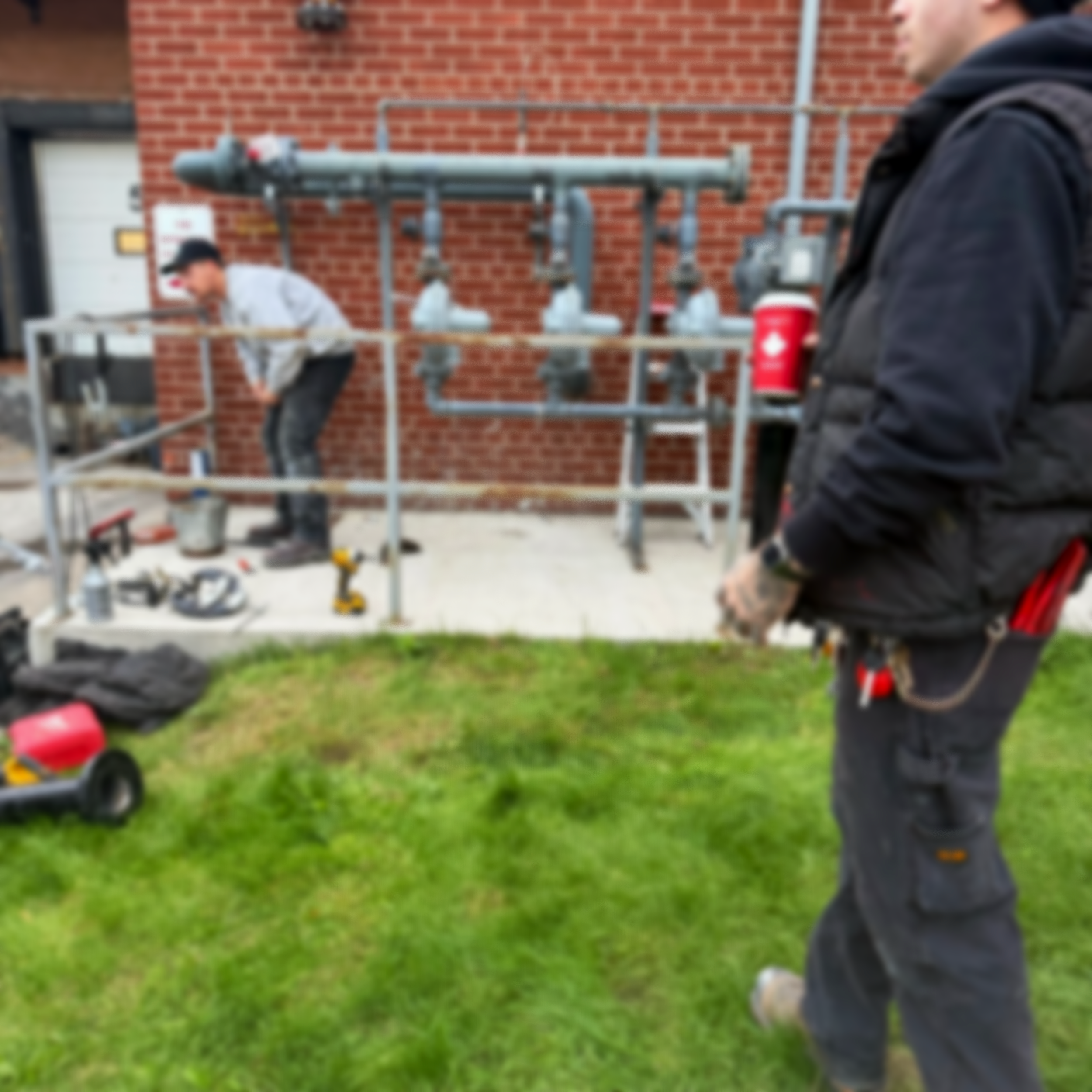 Workers setting up scaffolding outside a building with a brick exterior.