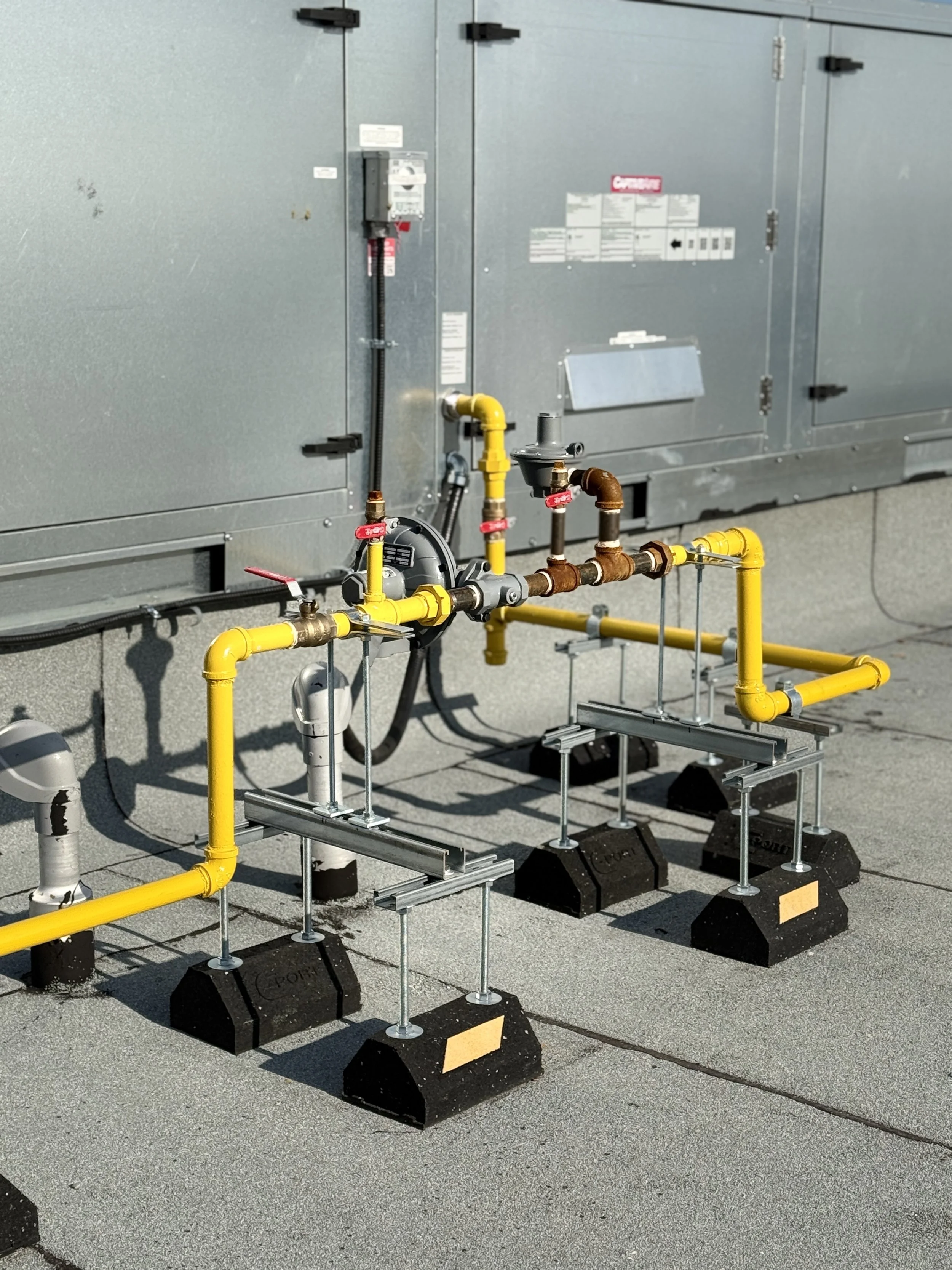 Colored pipes and valves outside an industrial HVAC unit.