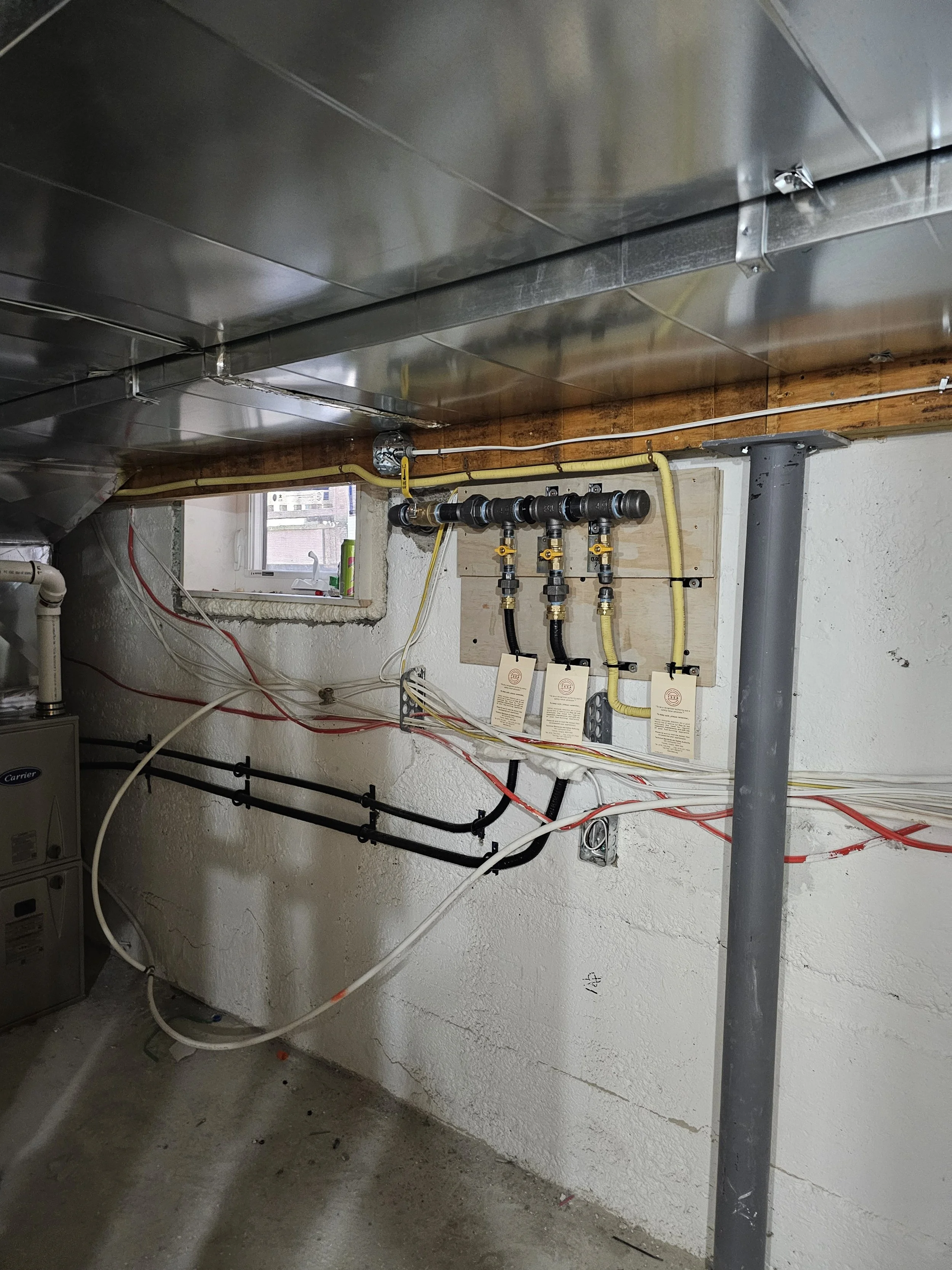 Basement utility room with plumbing and electrical wiring, a small window, and a concrete floor.
