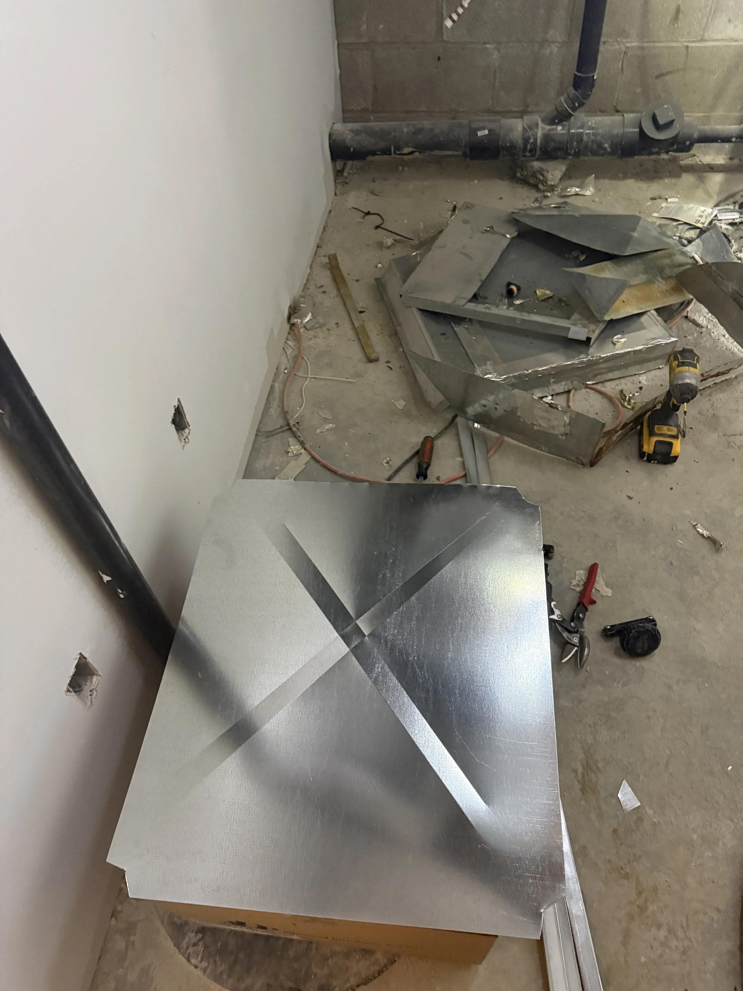 Construction site with metal sheets, tools, wires, and unfinished walls.