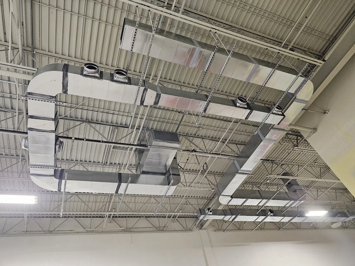 Metal HVAC ductwork and ventilation system installed on a ceiling in an industrial or commercial building.