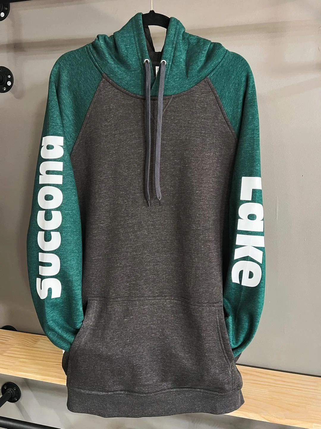 Gray hoodie with green sleeves and hood, featuring the word 'SUCC' written in large white letters on each sleeve.