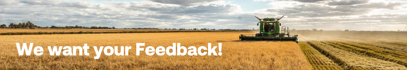 A green combine harvester working in a vast golden wheat field under a partly cloudy sky.