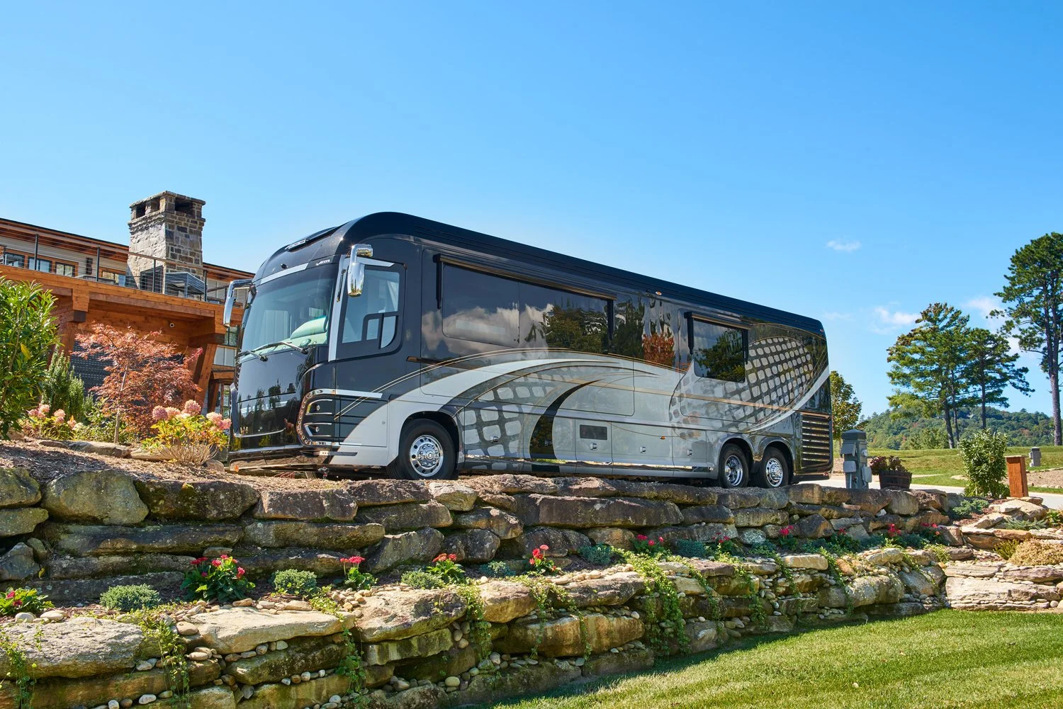 Newell Coach luxury RV parked on a stone wall in front of an upscale lodge.