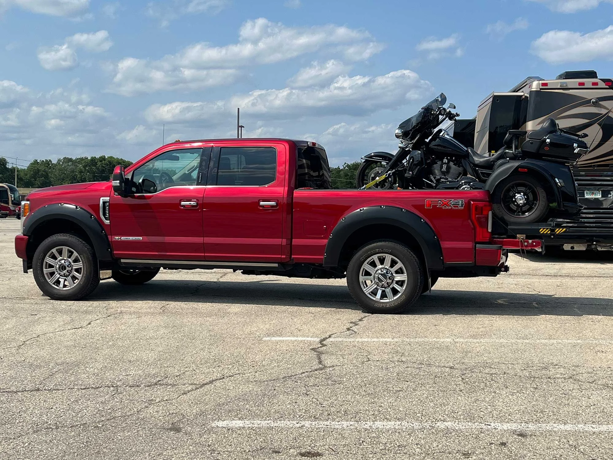 A red pickup truck with a motorcycle loaded in its bed.