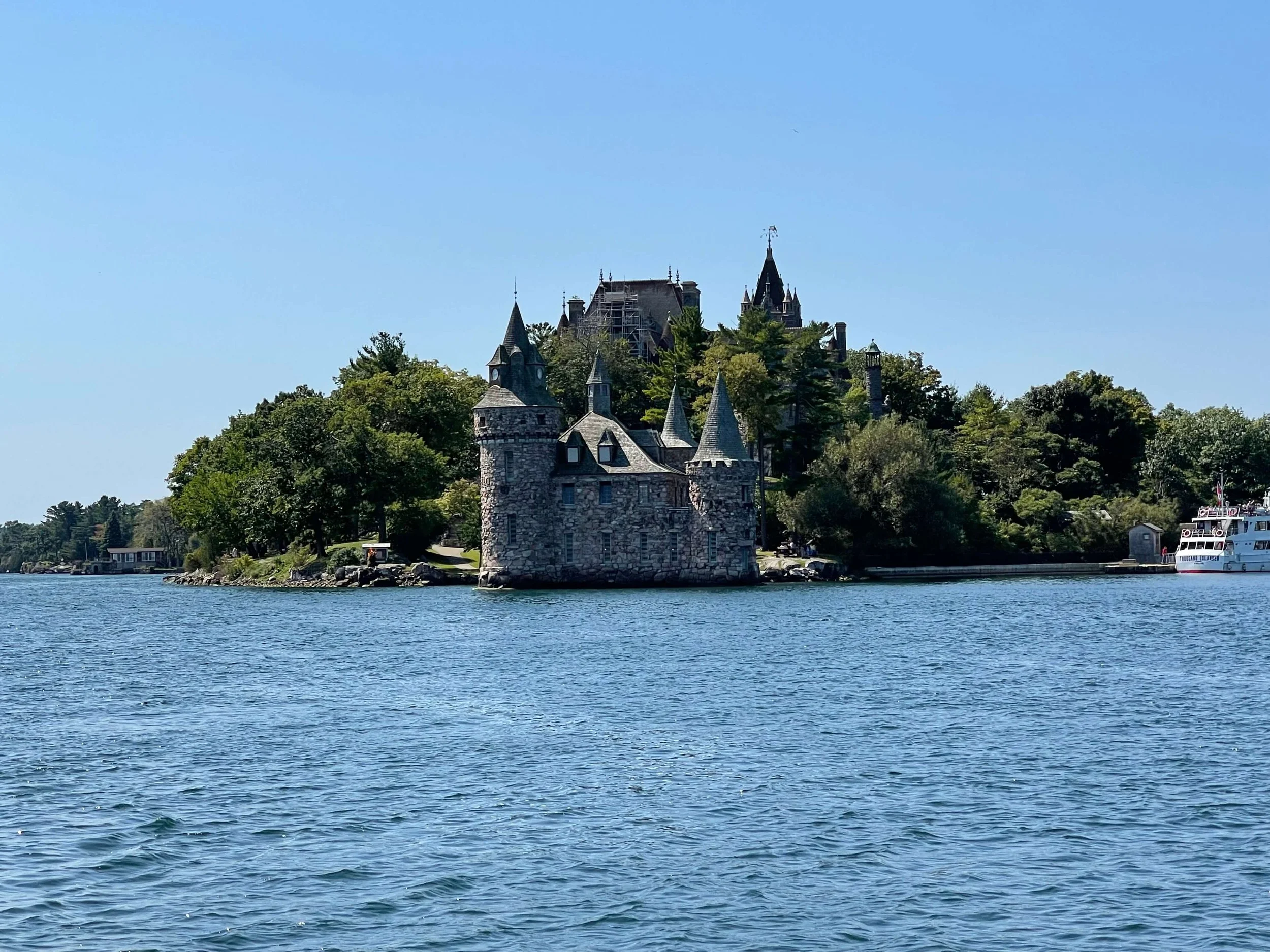 Scenic view of a historic stone castle on an island with a larger castle in the background.