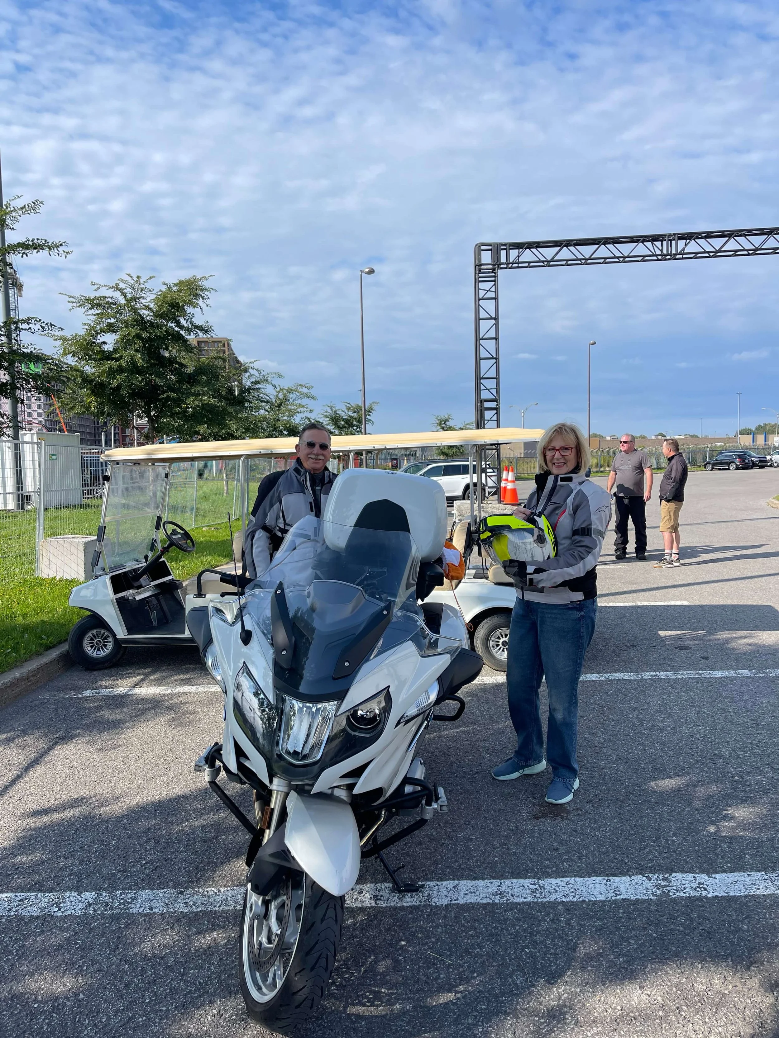 John and Karen Hawkins smiling behind their BMW motorcycle. 