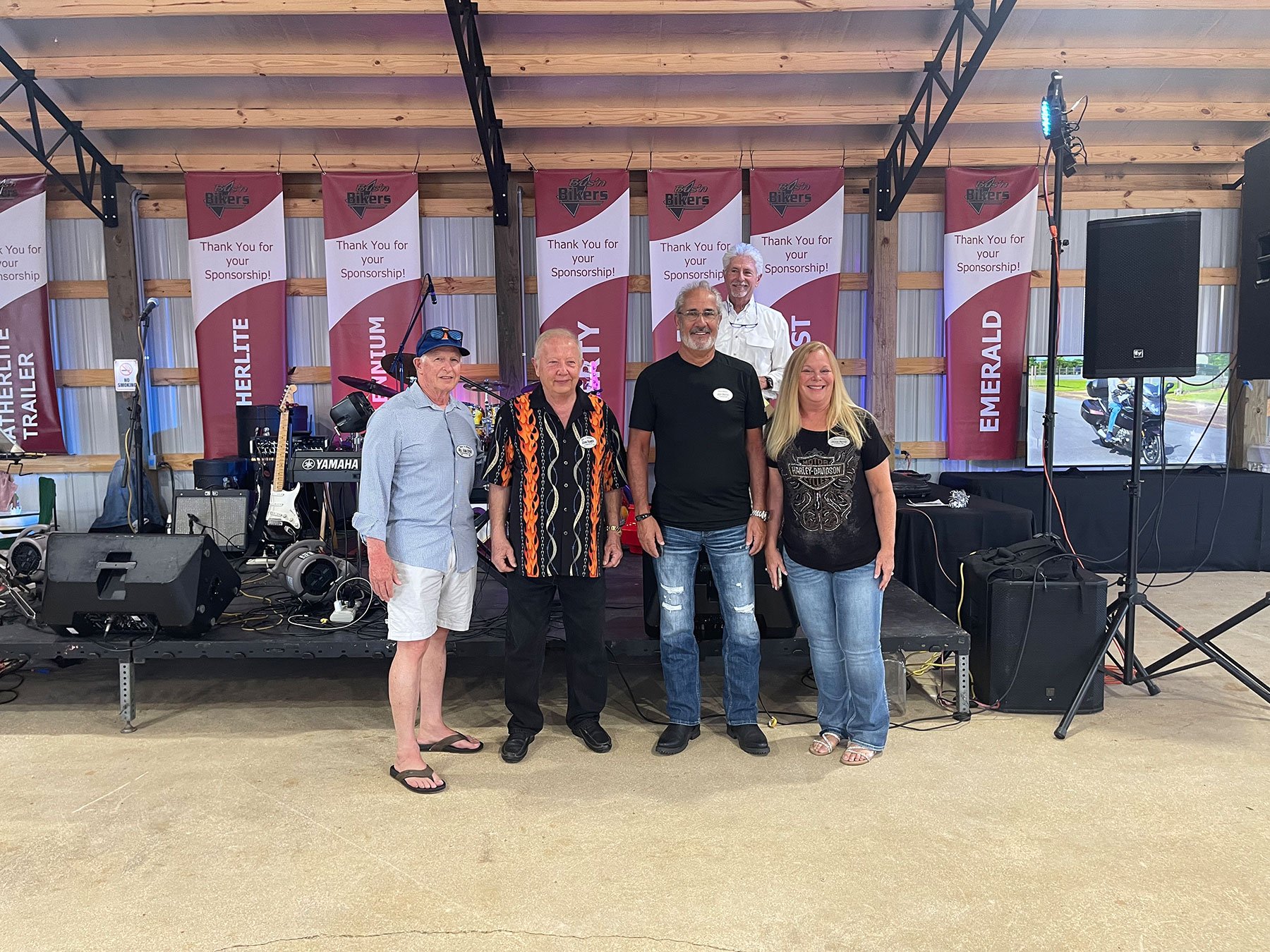 Group of rally sponsors standing together on stage at a motorcycle event.