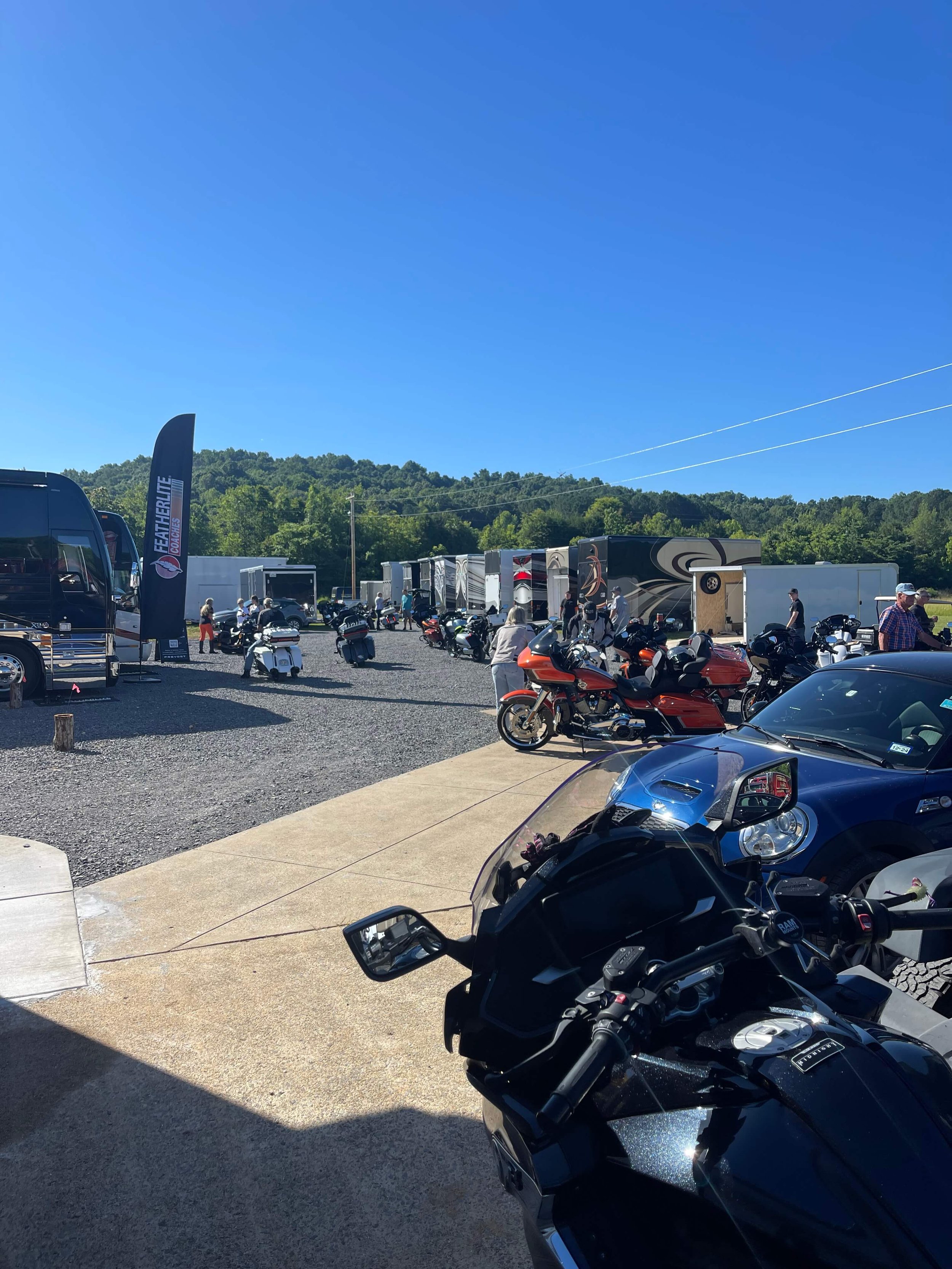 Motorcycles parked at an outdoor rally with trailers.