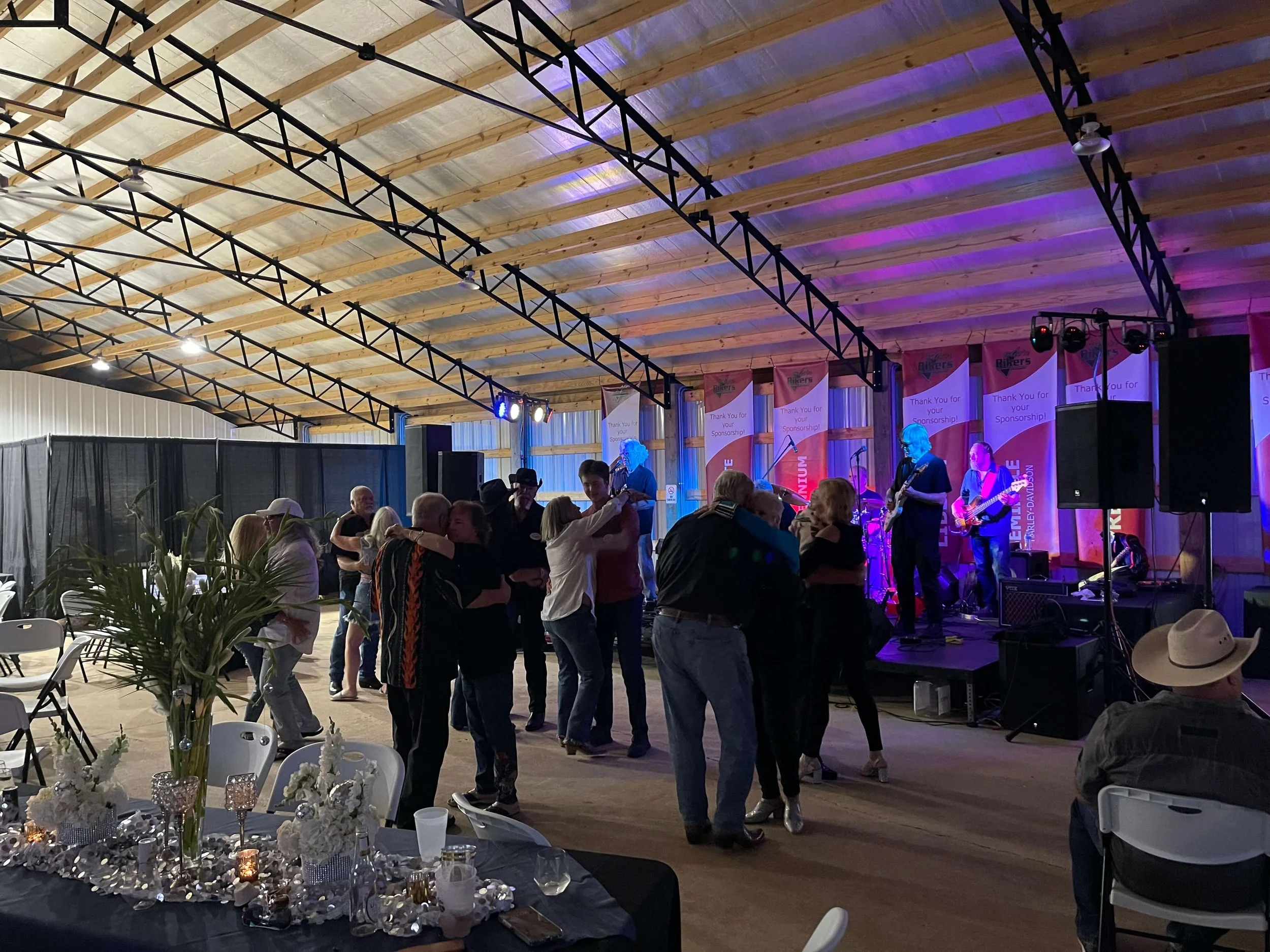 Guests dancing and enjoying live music at a covered rally event in a spacious venue.
