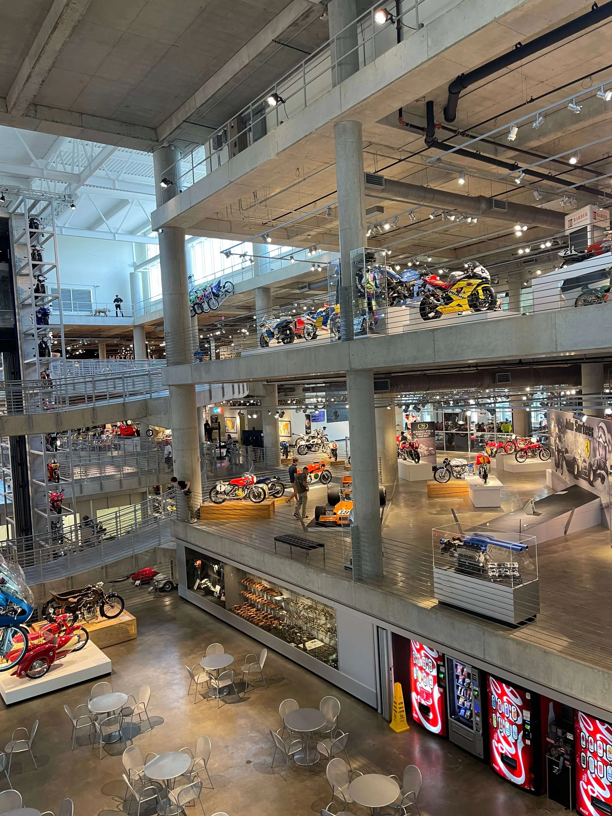 Aerial view of a motorcycle museum with multi-level exhibits and visitors.
