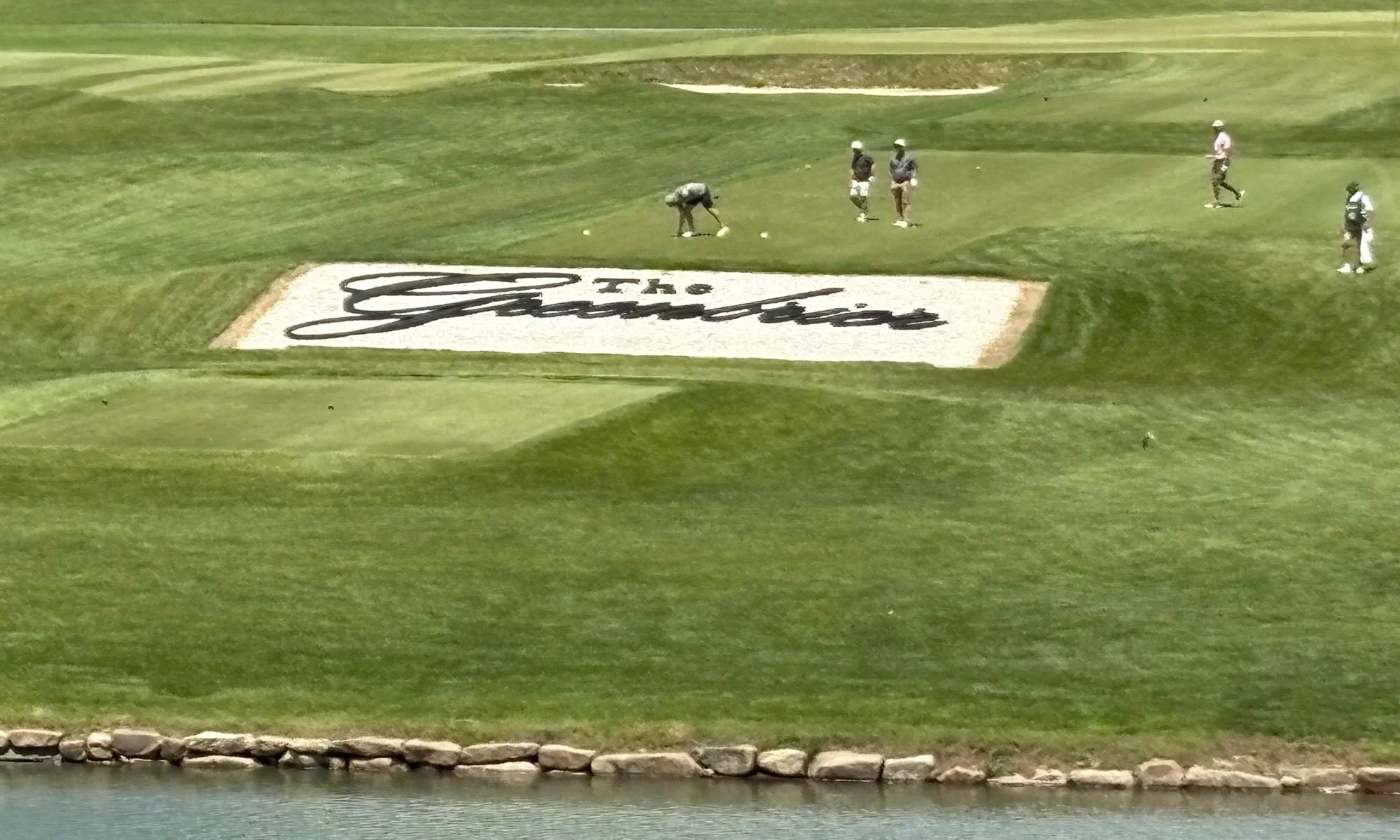 Golfers on a green next to a sand trap with "The Greenbrier" in script.