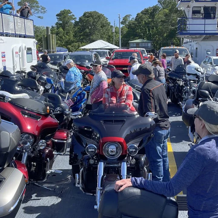 Motorcycles and riders loading onto a crowded ferry boat.