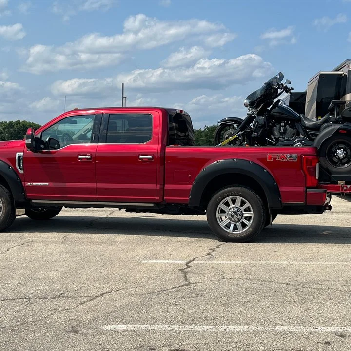 Red Ford truck hauling a black motorcycle.