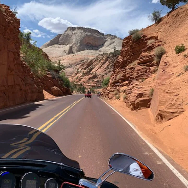 Motorcycle rider POV on scenic highway through red rock canyon.