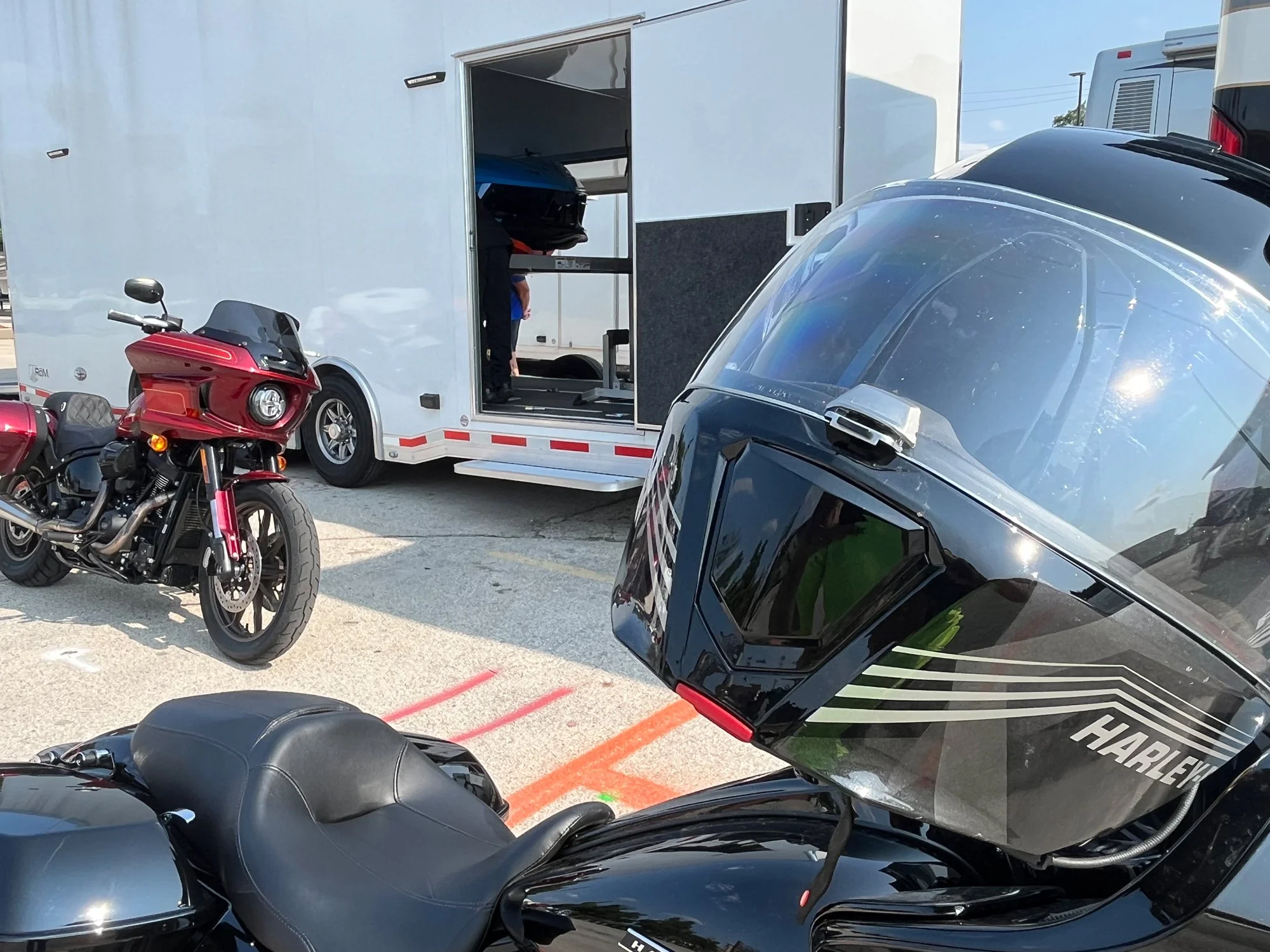 Multiple Harley-Davidson touring motorcycles parked beside Bus'n Bikers luxury motorcoach with open cargo bay during club trip.