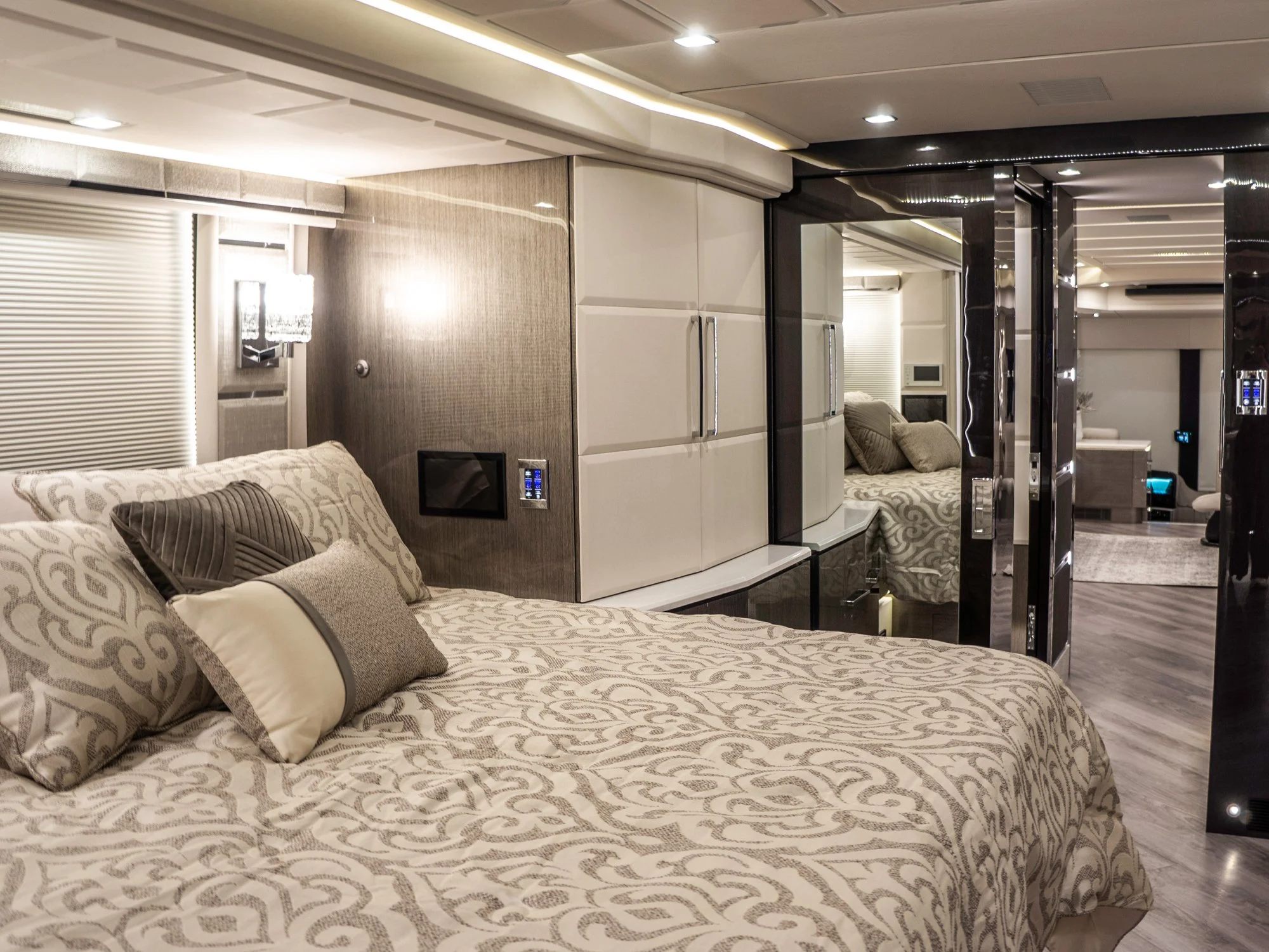 v2.jpg	Luxury motorhome bedroom with a large bed, patterned comforter, and mirrored closet.