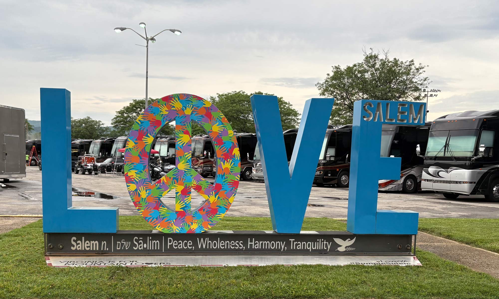 Salem LOVE metal sculpture with luxury coaches in the background..