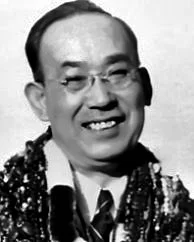 Black and white photo of a smiling man wearing glasses and a sparkly shirt.