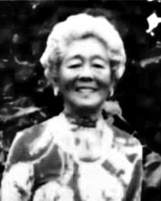 An elderly woman with gray curly hair smiling outdoors