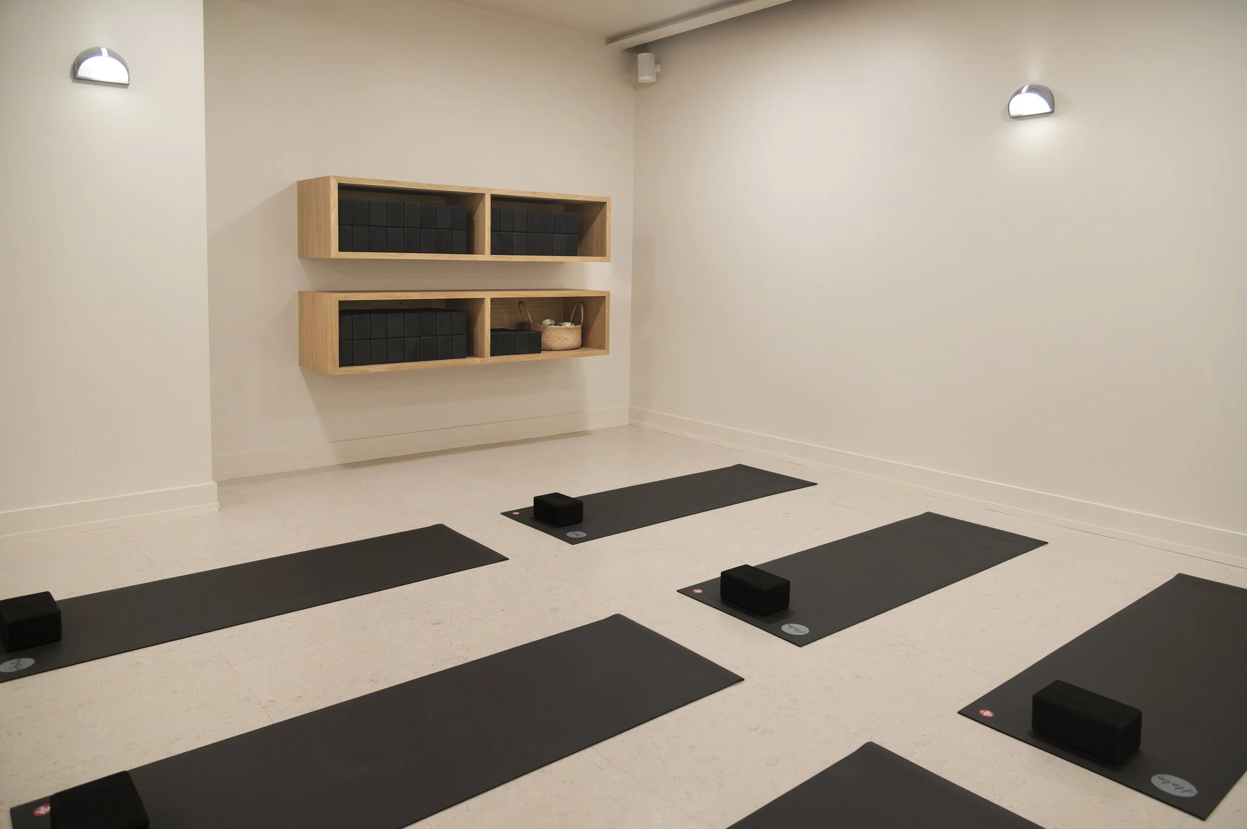 Modern interior space with a wooden reception desk, a large abstract artwork on the wall, and a tall glass vase with dried pampas grass near a window.