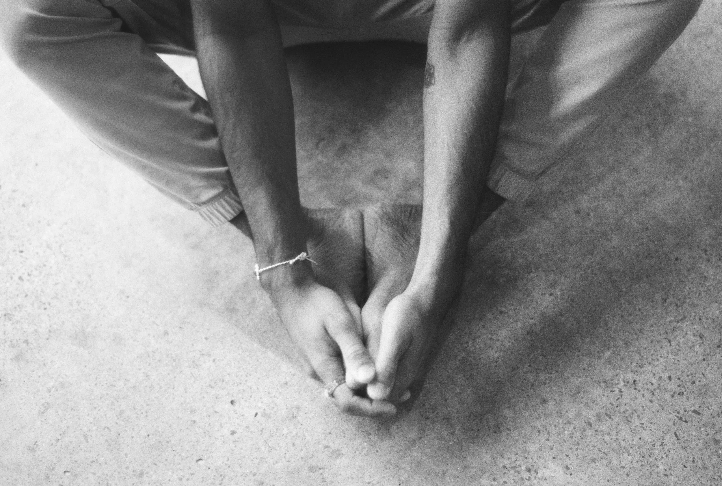 Two people sitting cross-legged on the floor, holding their hands together in a prayer-like gesture.