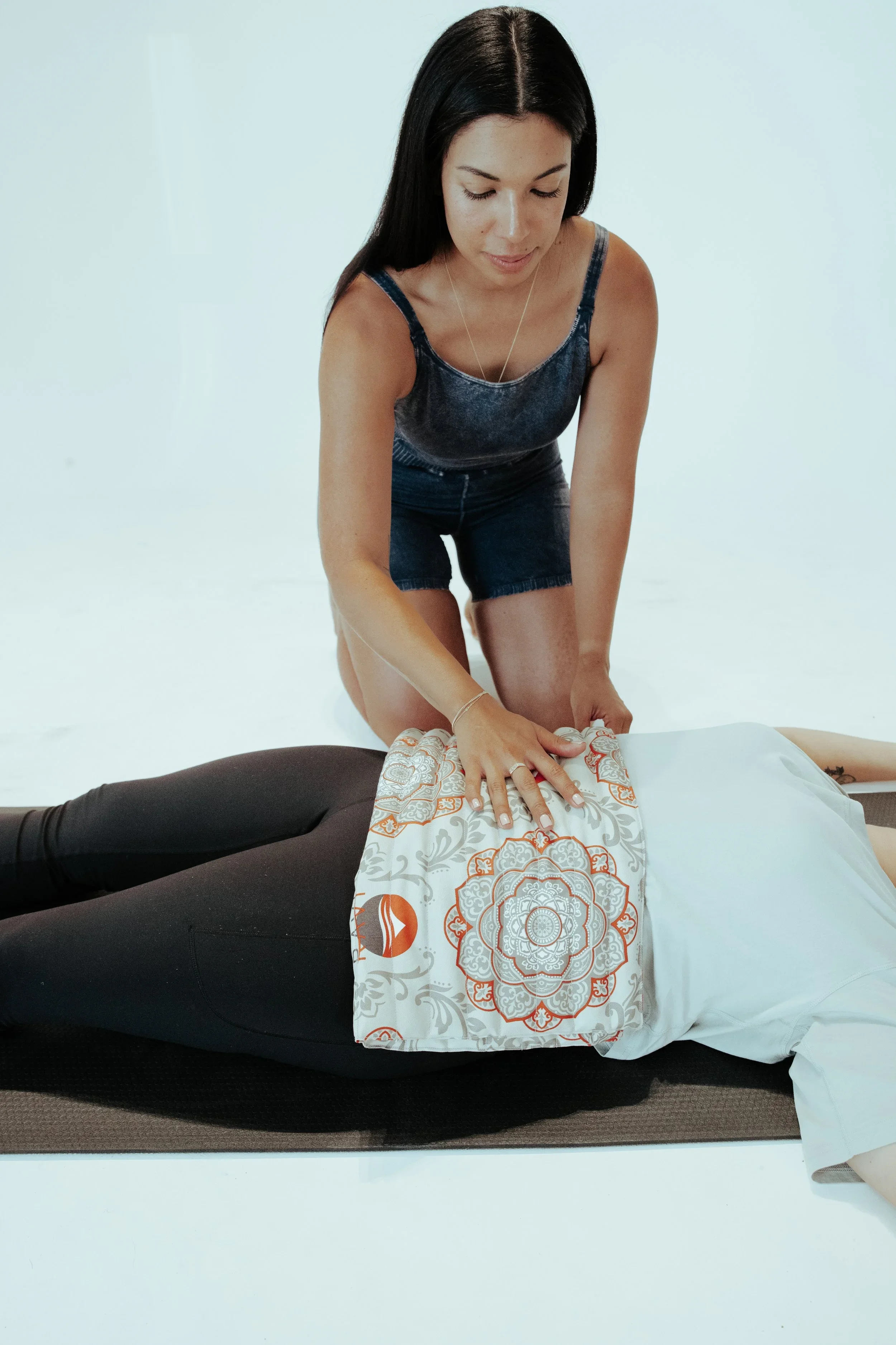 A woman is performing CPR on a person lying on the floor, with her hands on the person's chest, practicing chest compressions.