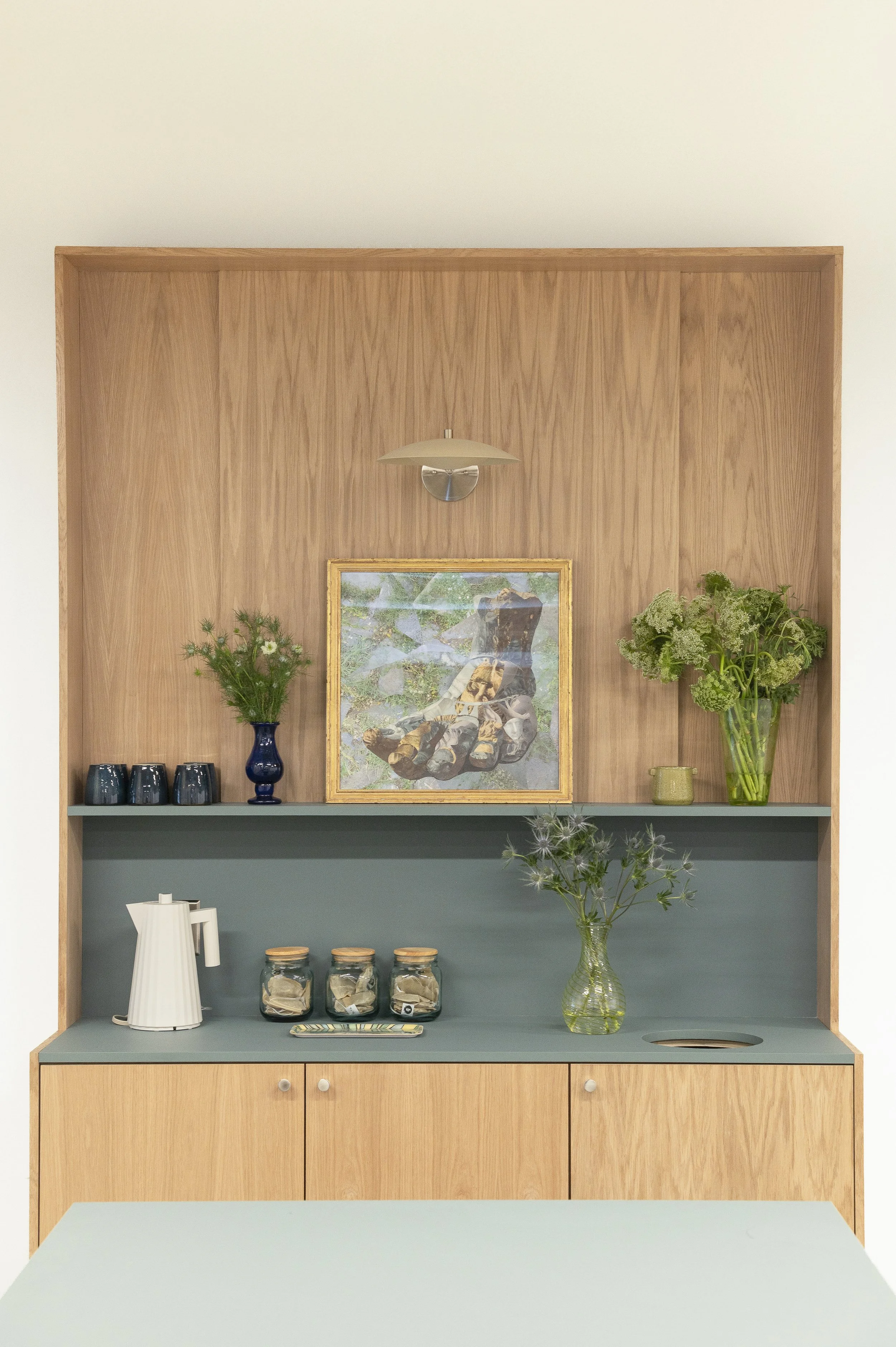 An empty yoga studio with sunlight streaming through large windows, yoga mats arranged on the floor with small wooden blocks, a ceiling fan, and white walls.