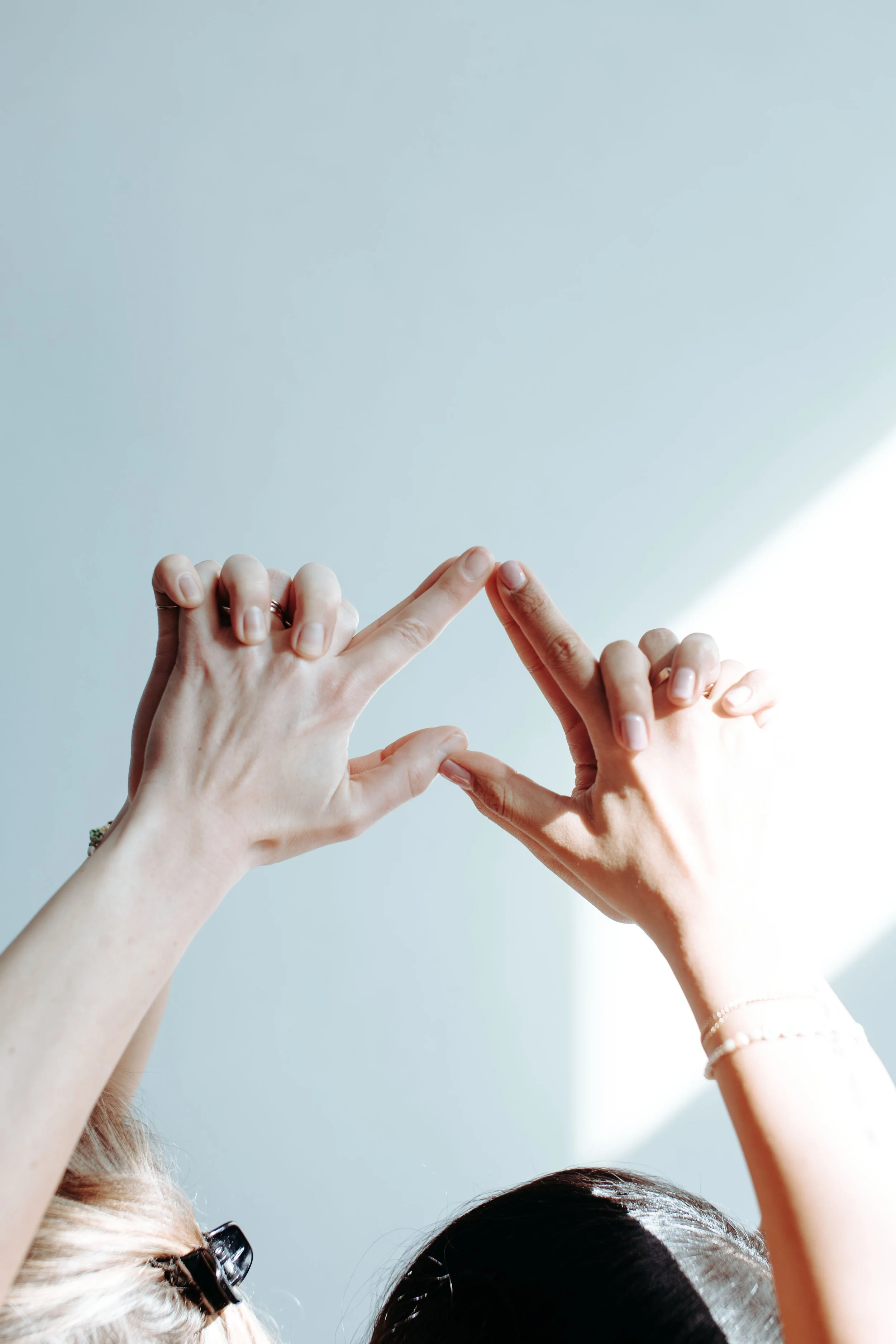 Two people forming a triangle with their hands against a light background.
