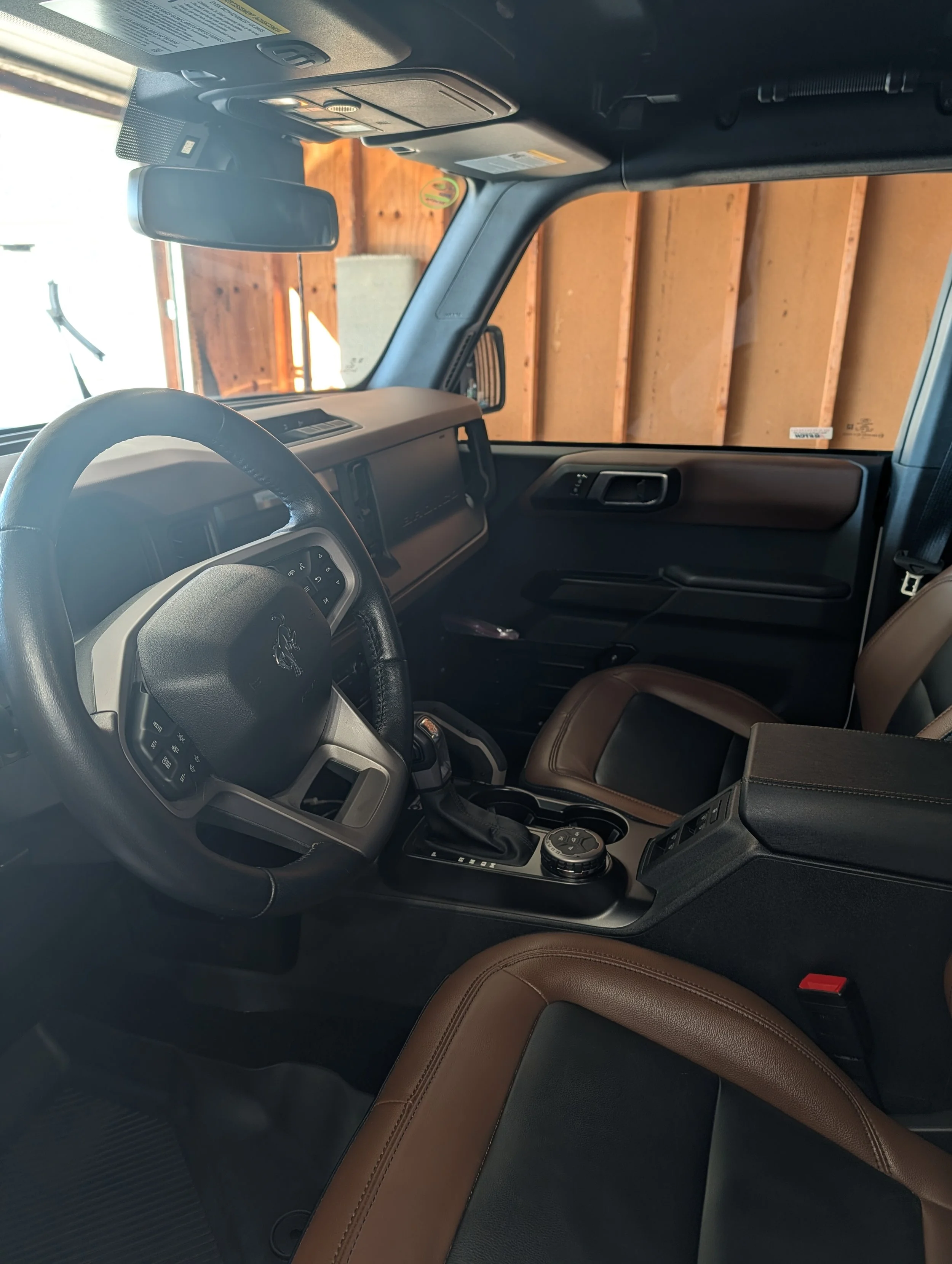 A modern house on a grassy hillside with a mountain range in the background under a cloudy sky.