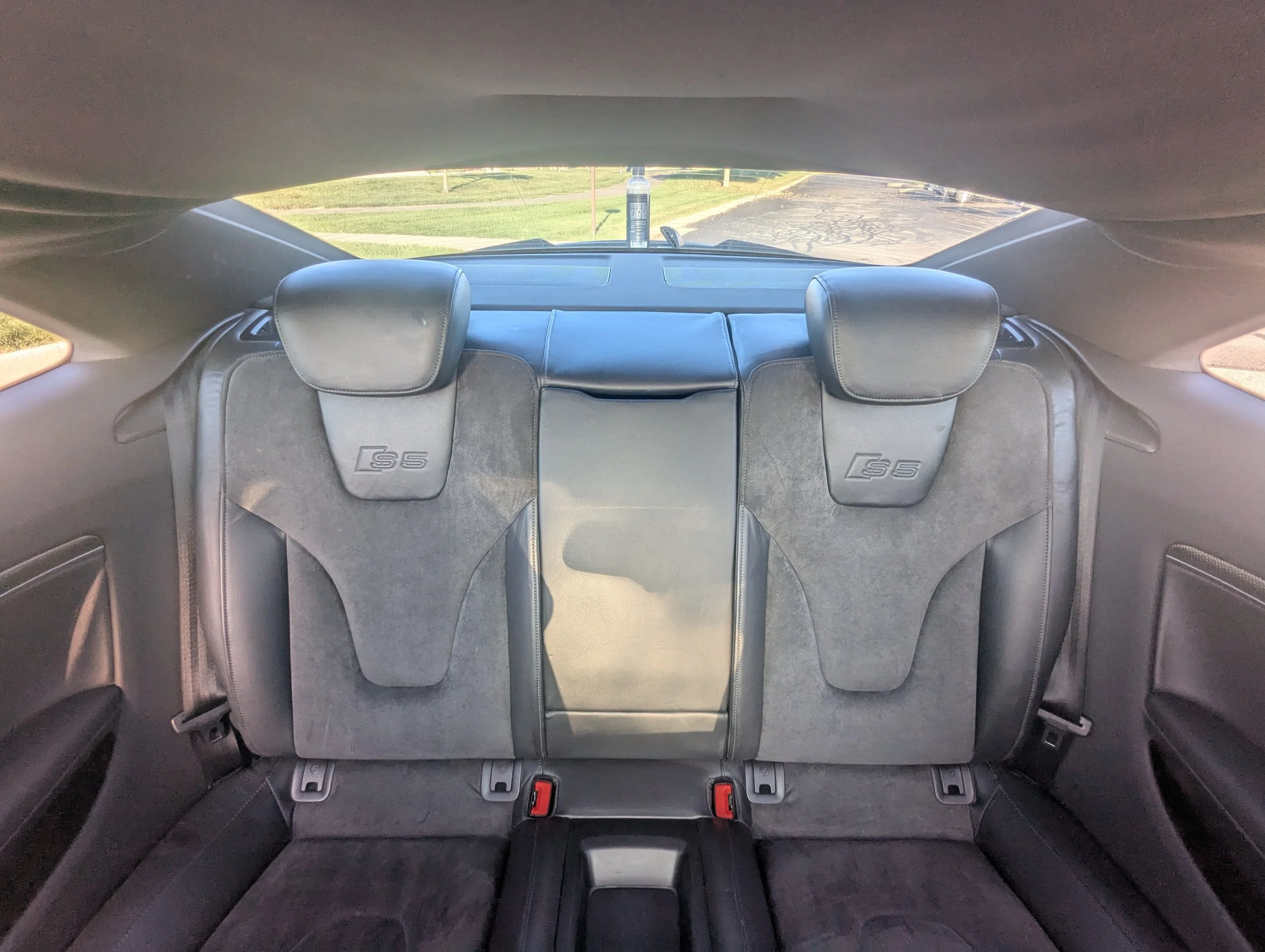 The back seats of an Audi S5 car, showing black leather and suede upholstery with headrests that have the 'S5' logo on them.