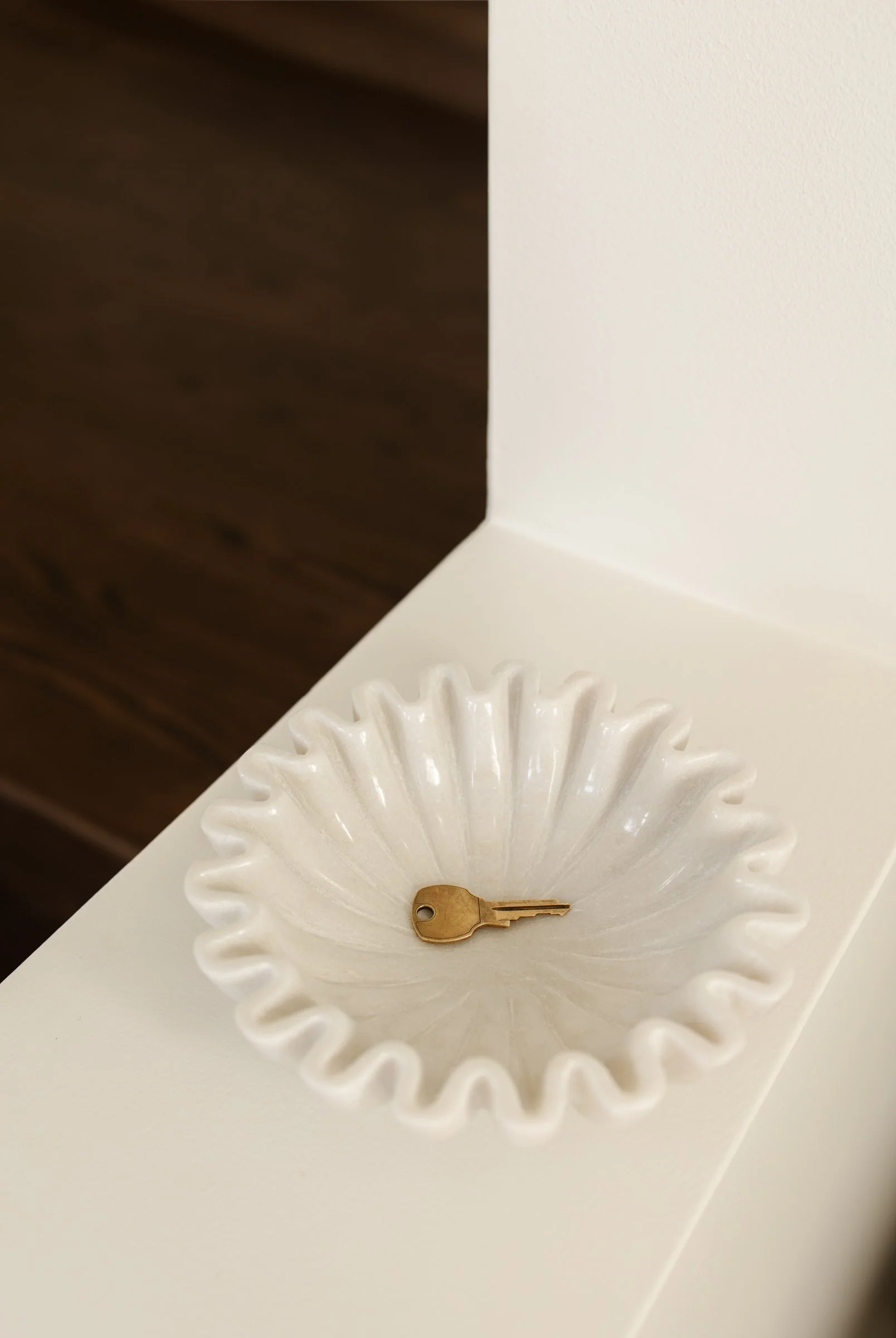 A single brass key rests in a white, wavy-edged ceramic dish in a Minneapolis therapist office—a symbol of discovery