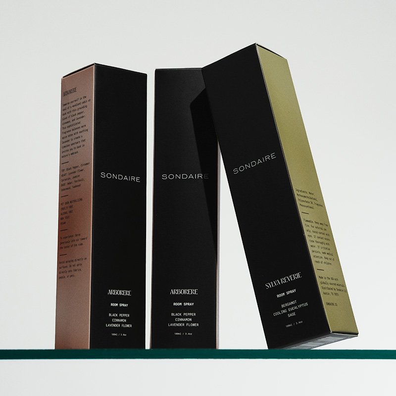 Three tall perfume boxes, black with different colored sides, standing upright on a shelf.