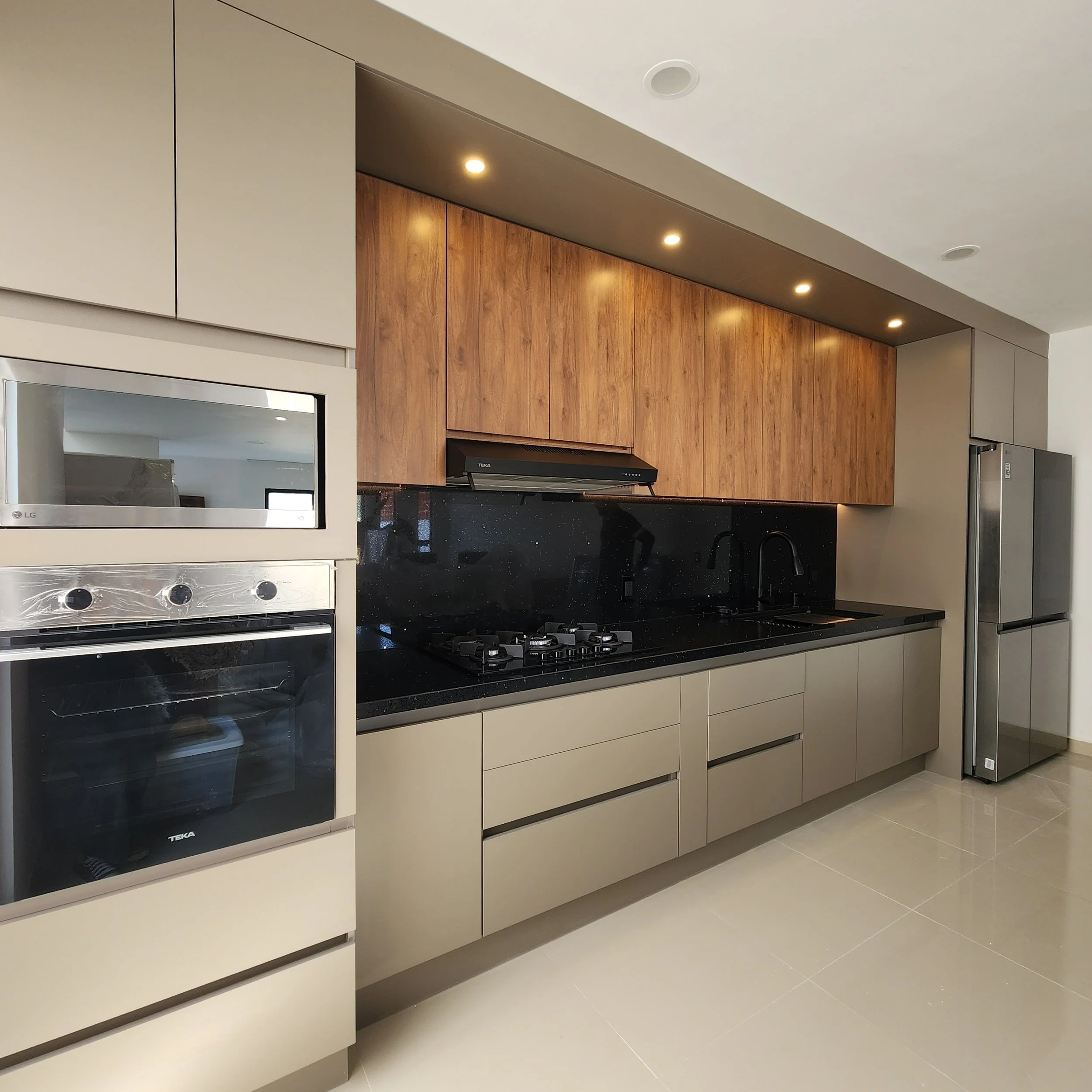 vista de una cocina moderna con gabinetes gris oscuro y de madera clara, un horno y cocina de gas en la encimera y electrodomésticos de acero inoxidable.