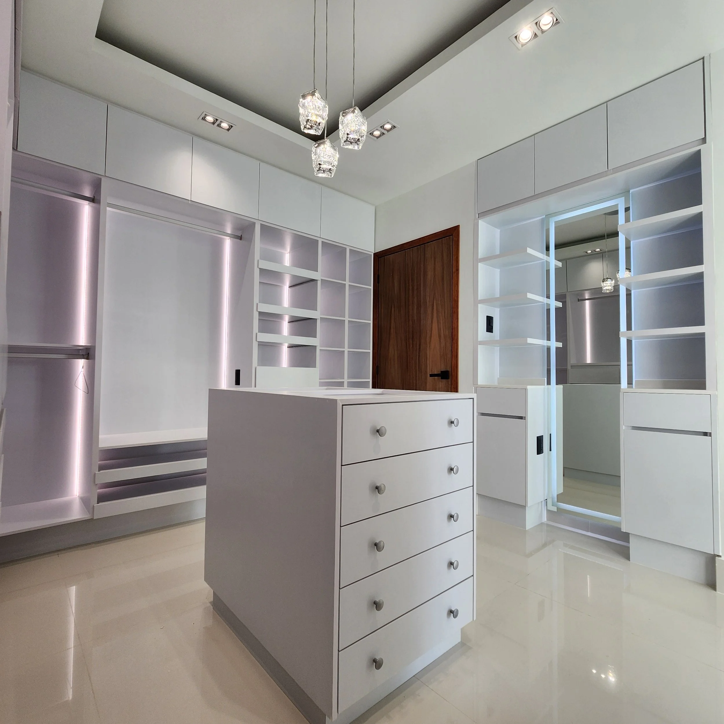 Armario blanco con puertas abiertas, estanterías y cajones en interior espacioso, en una habitación moderna con suelo brillante.