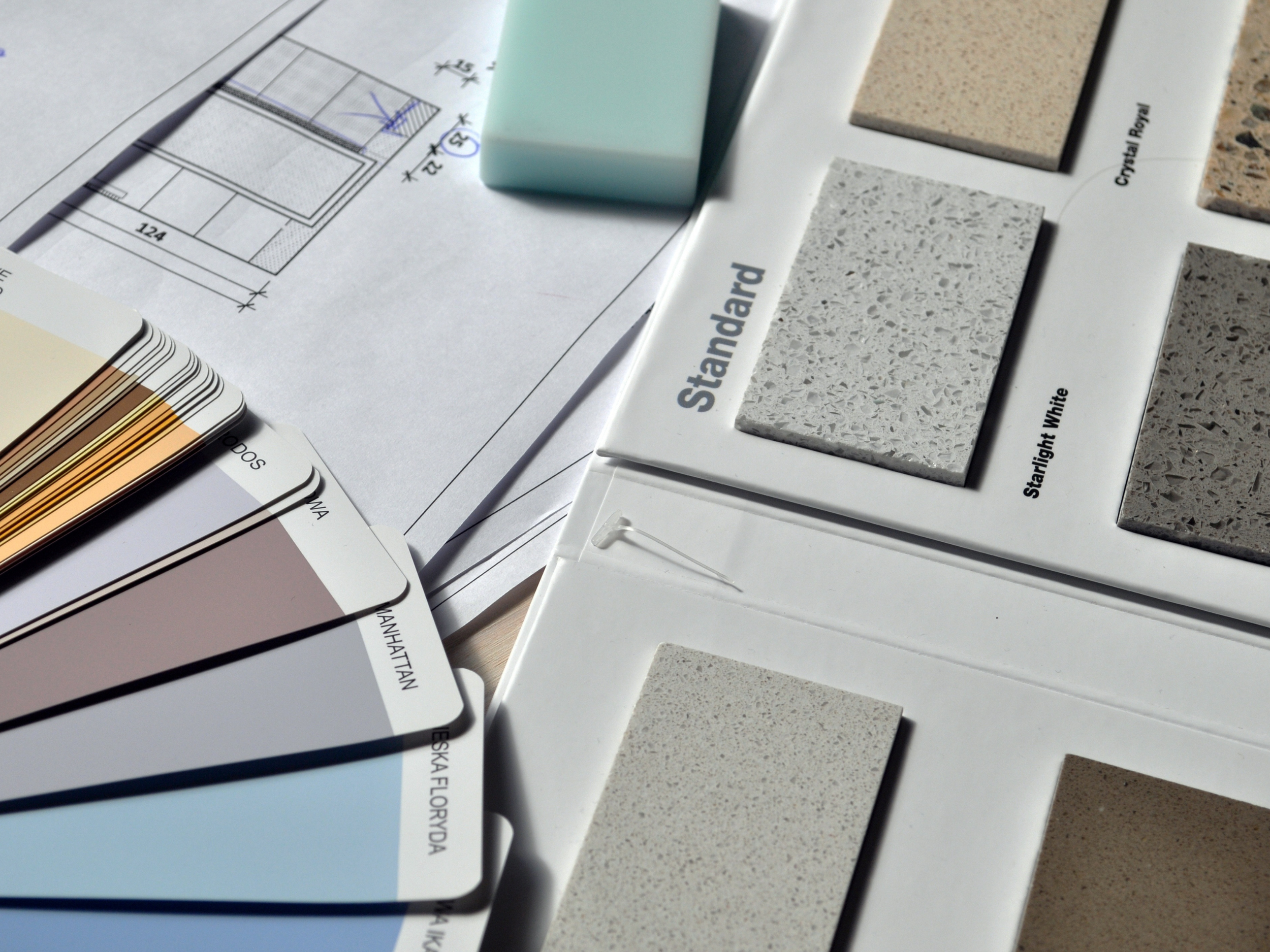 Samples of tile and countertop materials, color swatches, and a design plan on paper.