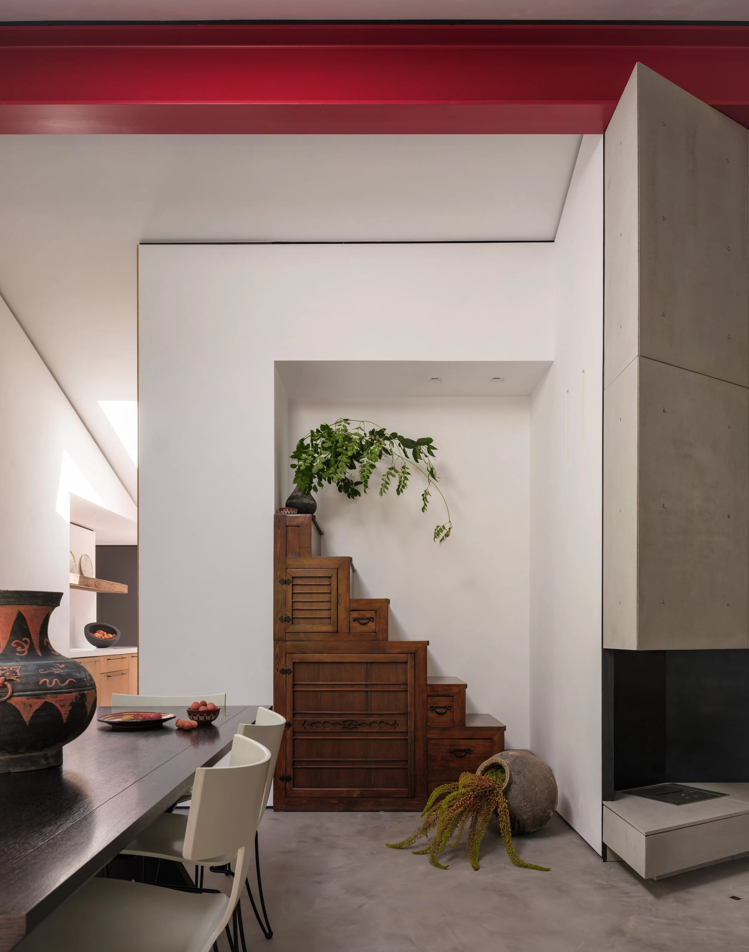 Interior view of a modern room with a wooden stairway, potted plant, and decorative pottery.