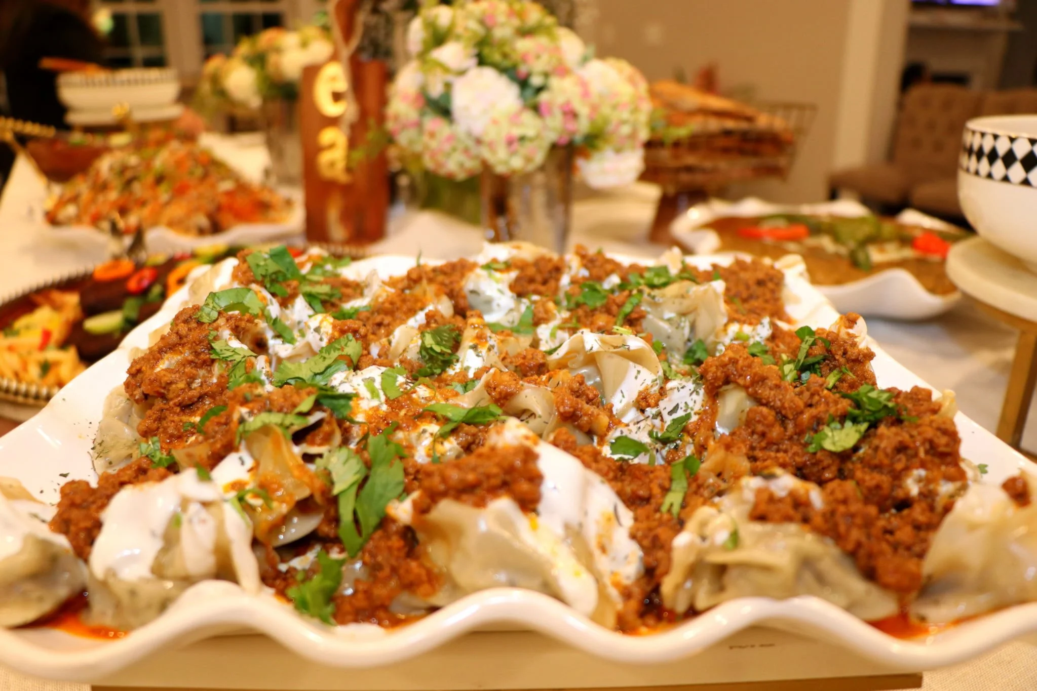 Plate of beef and vegetable dumplings topped with ground meat sauce and chopped parsley