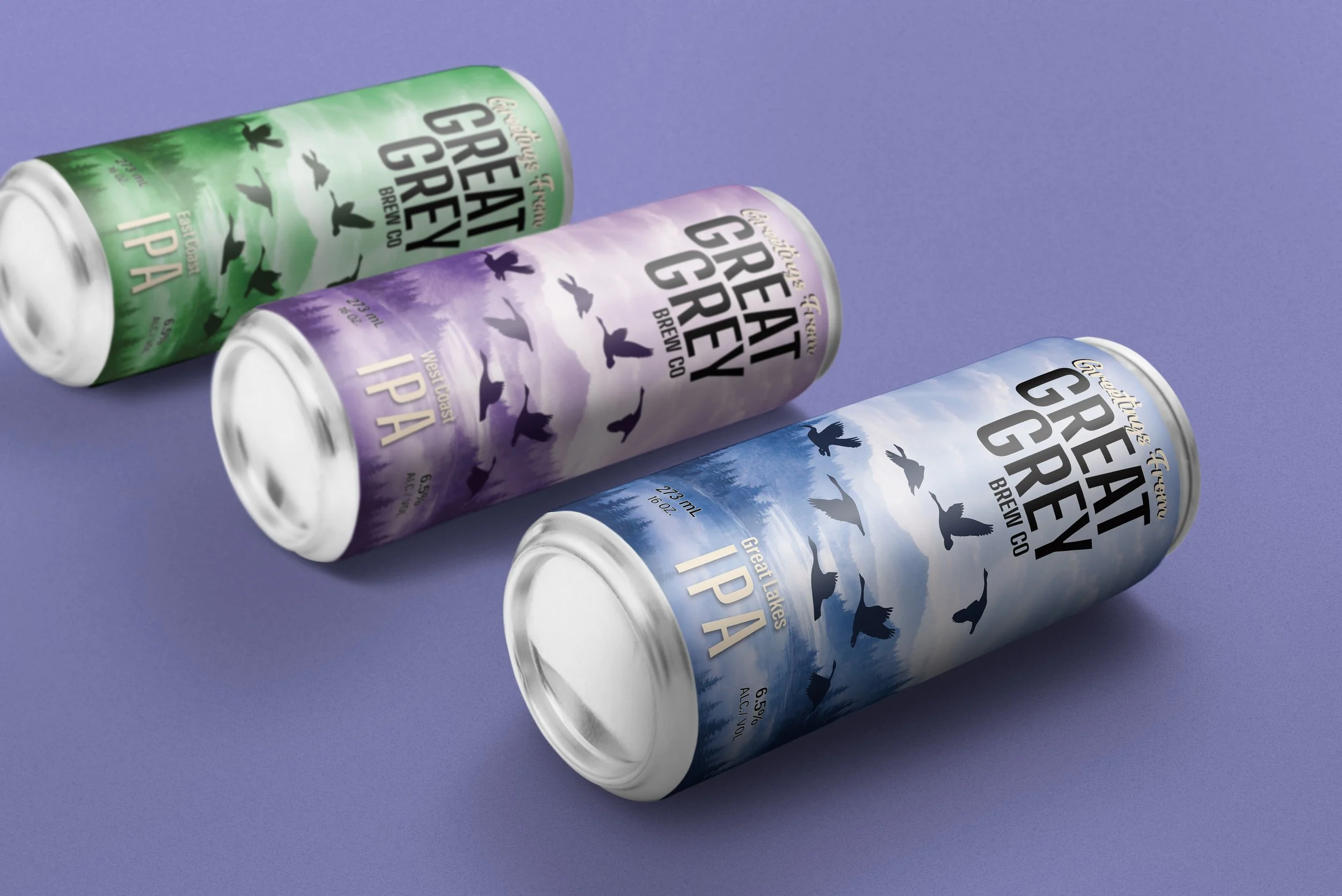 Three colorful cans of Great Lakes Brew Co. IPA beer with different mountain and bird designs, placed on a purple surface.