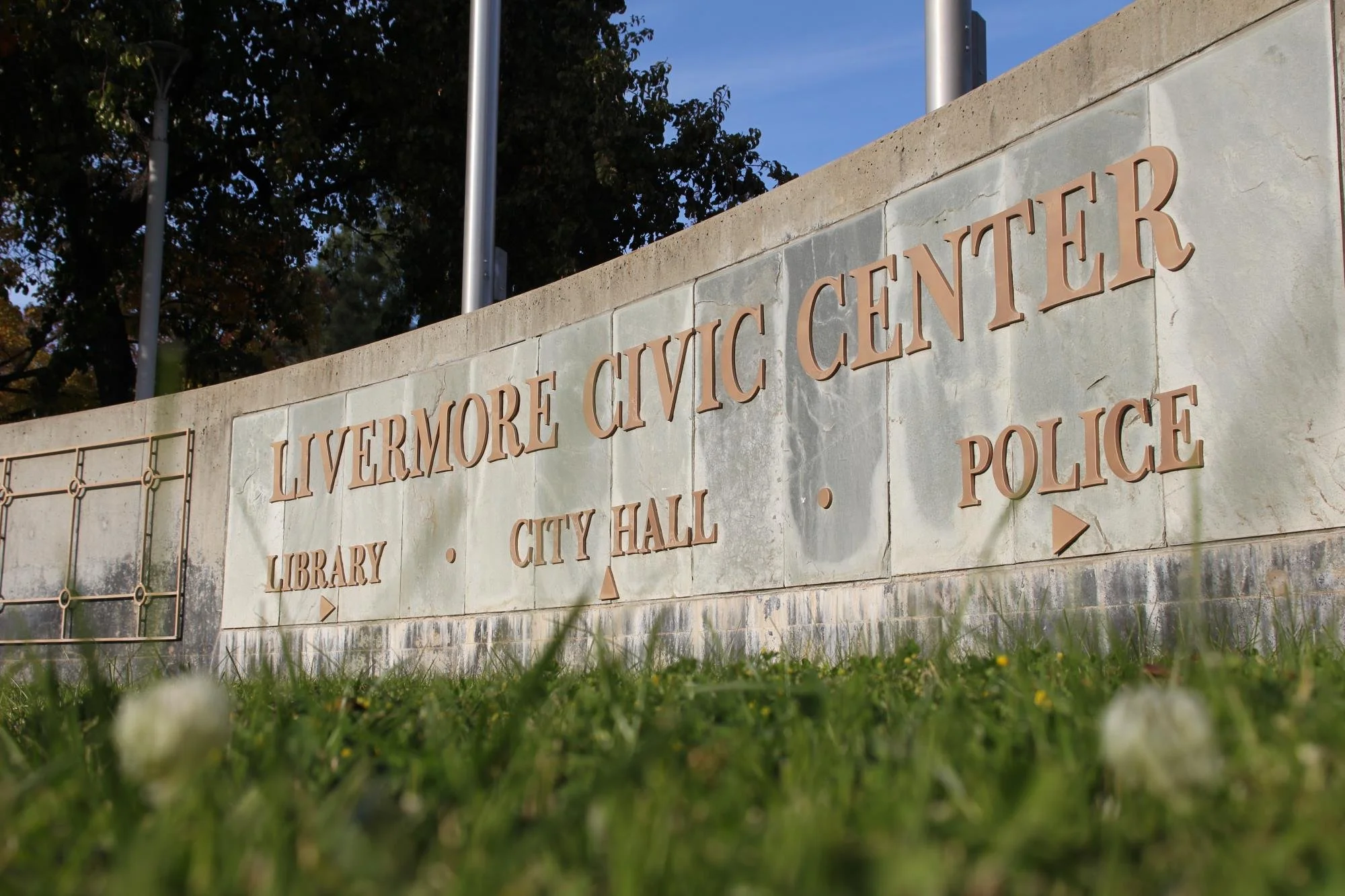 Sign on a wall reading 'LIVERMORE CIVIC CENTER' with directions to 'LIBRARY,' 'CITY HALL,' and 'POLICE' beneath, outdoors during daytime.