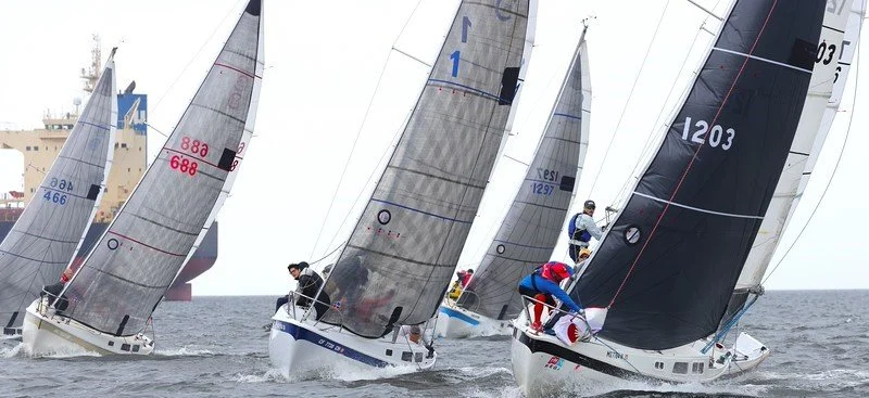Sailing boats racing on open water with crew members onboard