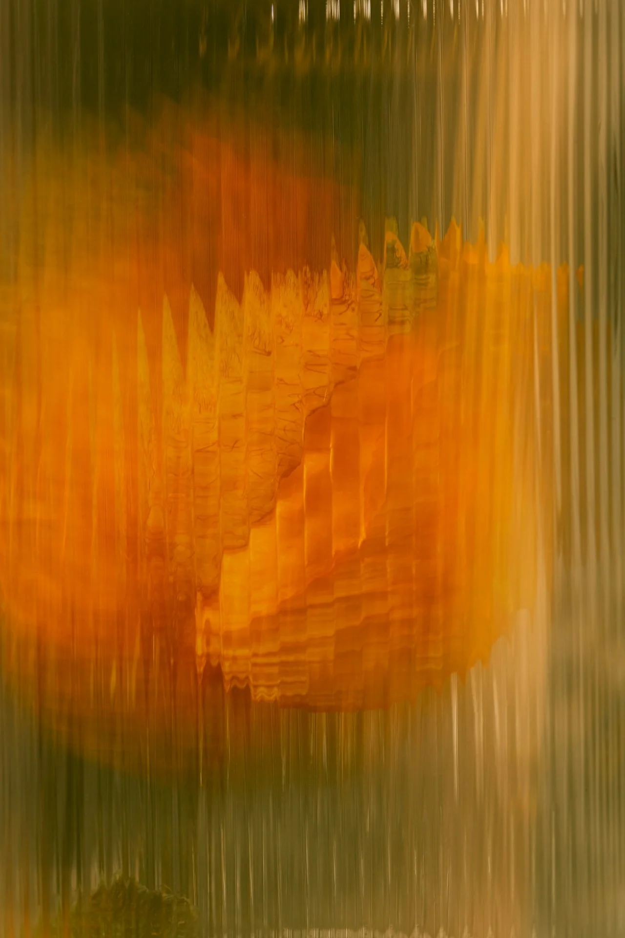 Abstract image with vertical streaks of orange, yellow, and green colors, creating a blurred or distorted appearance.