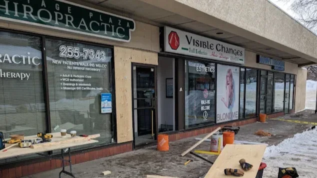 Unfinished storefront construction with signs for chiropractic and aesthetic services, boarded-up window, orange buckets, yellow caution tape, and construction tools outside.