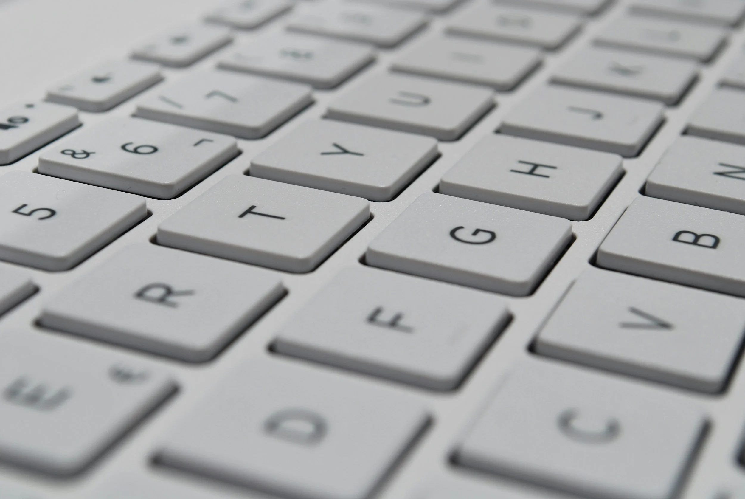 Close-up of a white computer keyboard with gray keys, focusing on the J, H, G, and V keys.