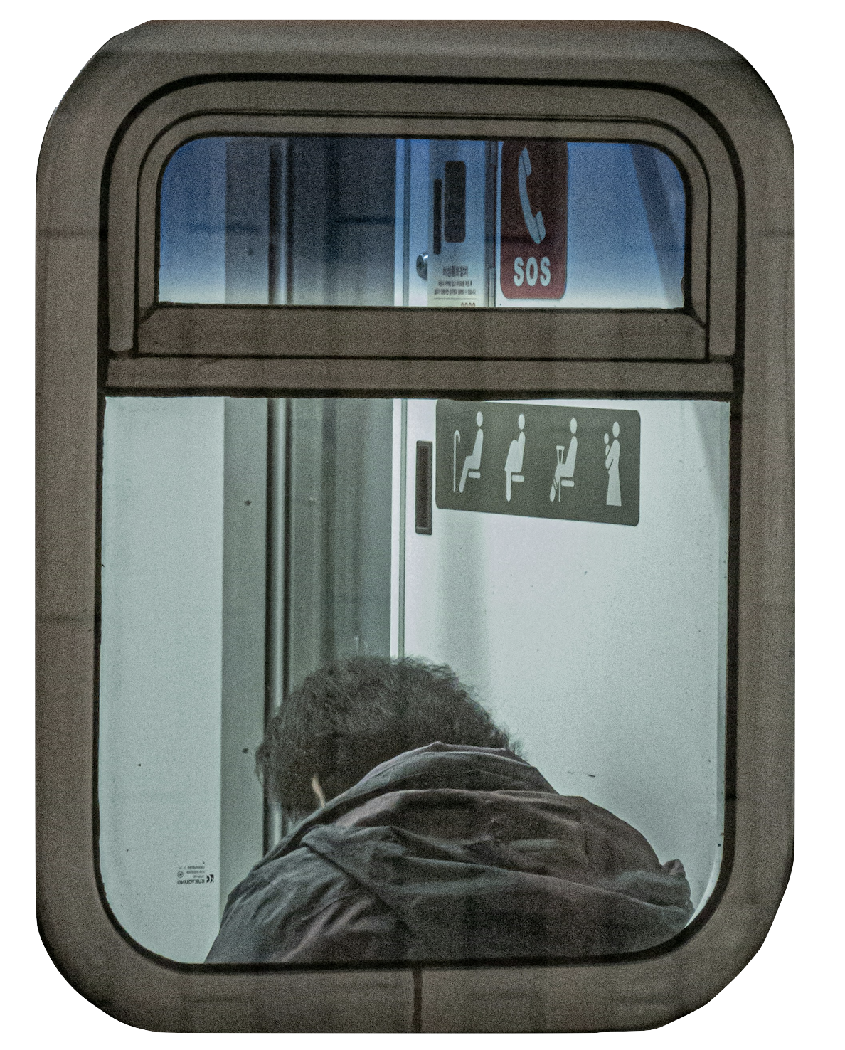 A person with black hair and a jacket sitting inside a bus near a window, seen from outside through the window, with safety sign icons and an SOS sign visible inside.