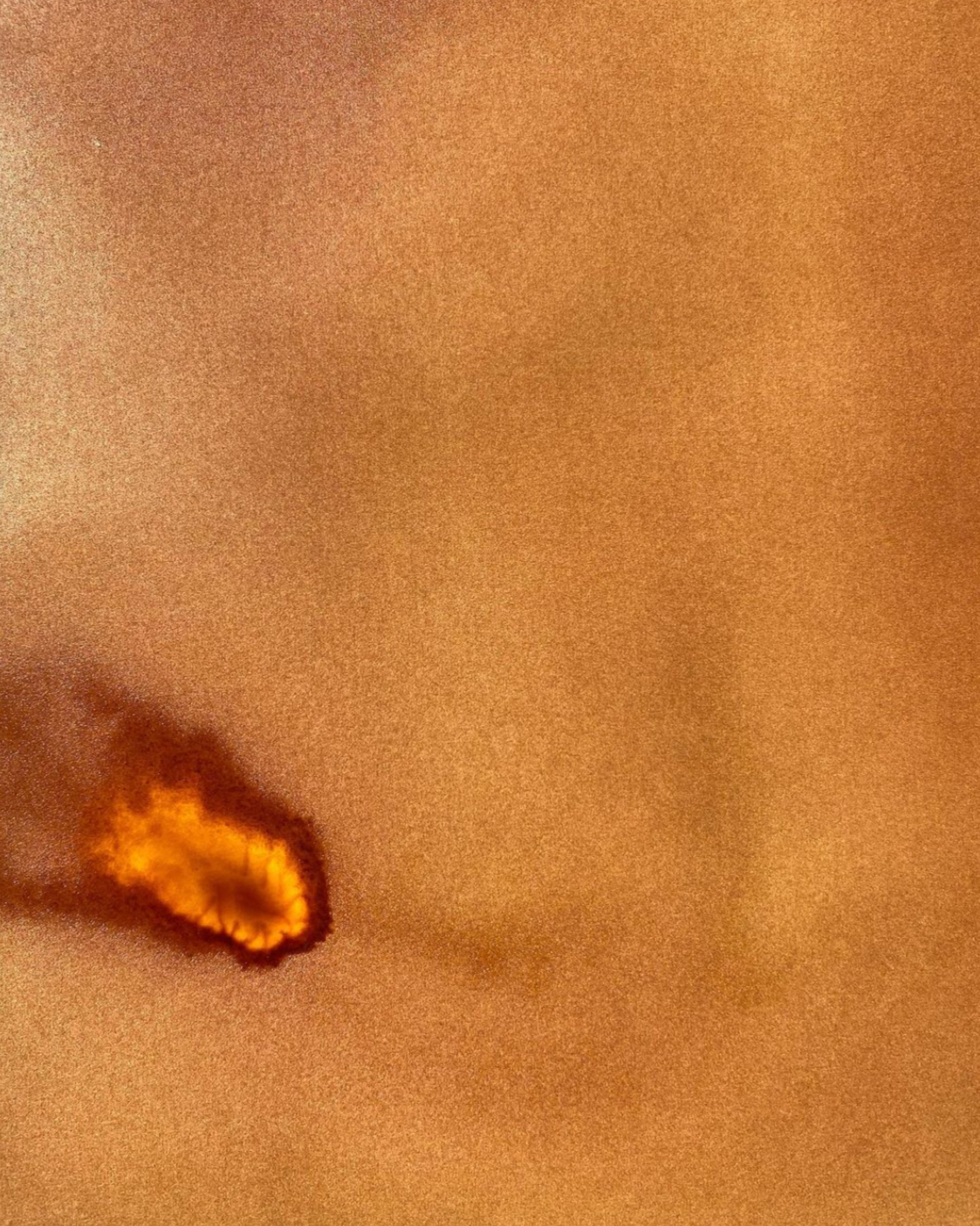 Close-up of a floating flame or fire against a brown, sandy textured background.