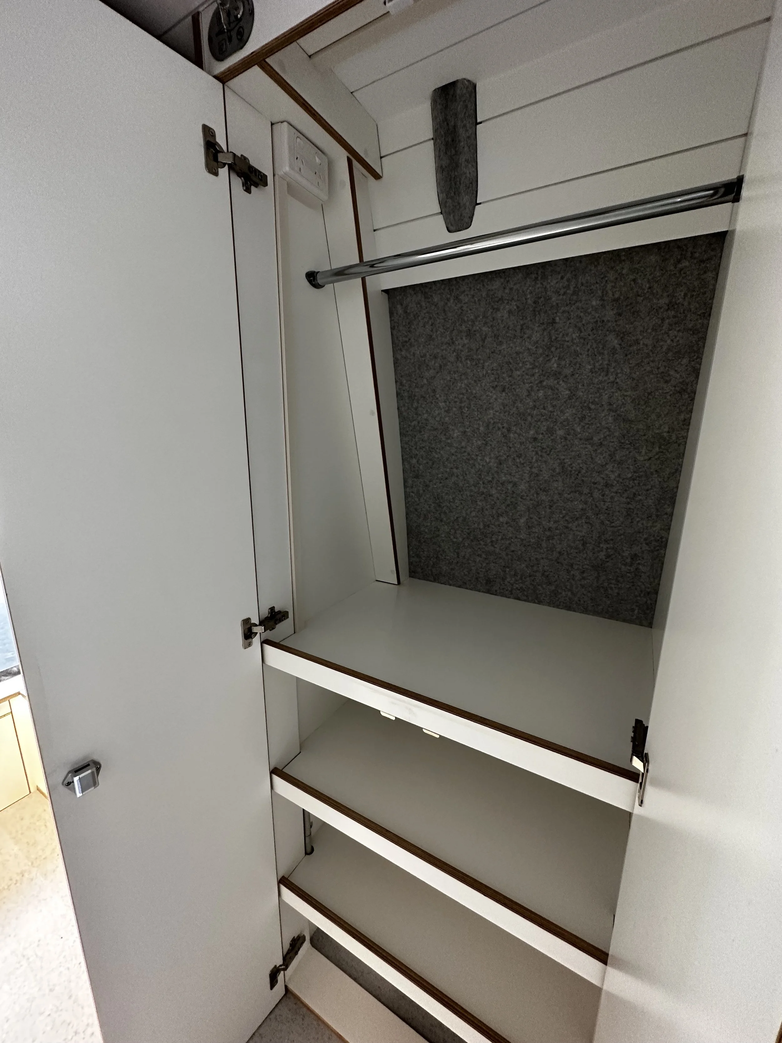 Empty white closet with shelves, a hanging rod, and a gray felt lining at the back.